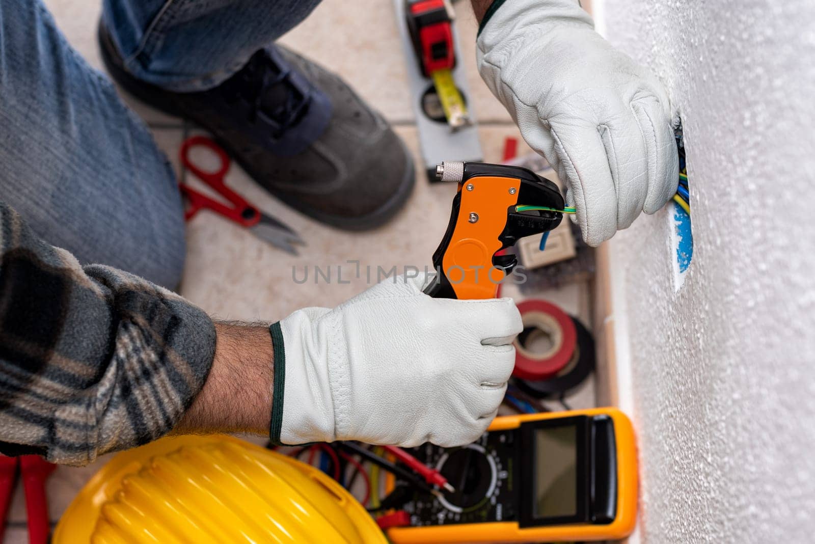 Top view. Electrician worker at work with wire stripper prepares the electrical cables of an electrical system. Working safely with protective gloves. Construction industry.