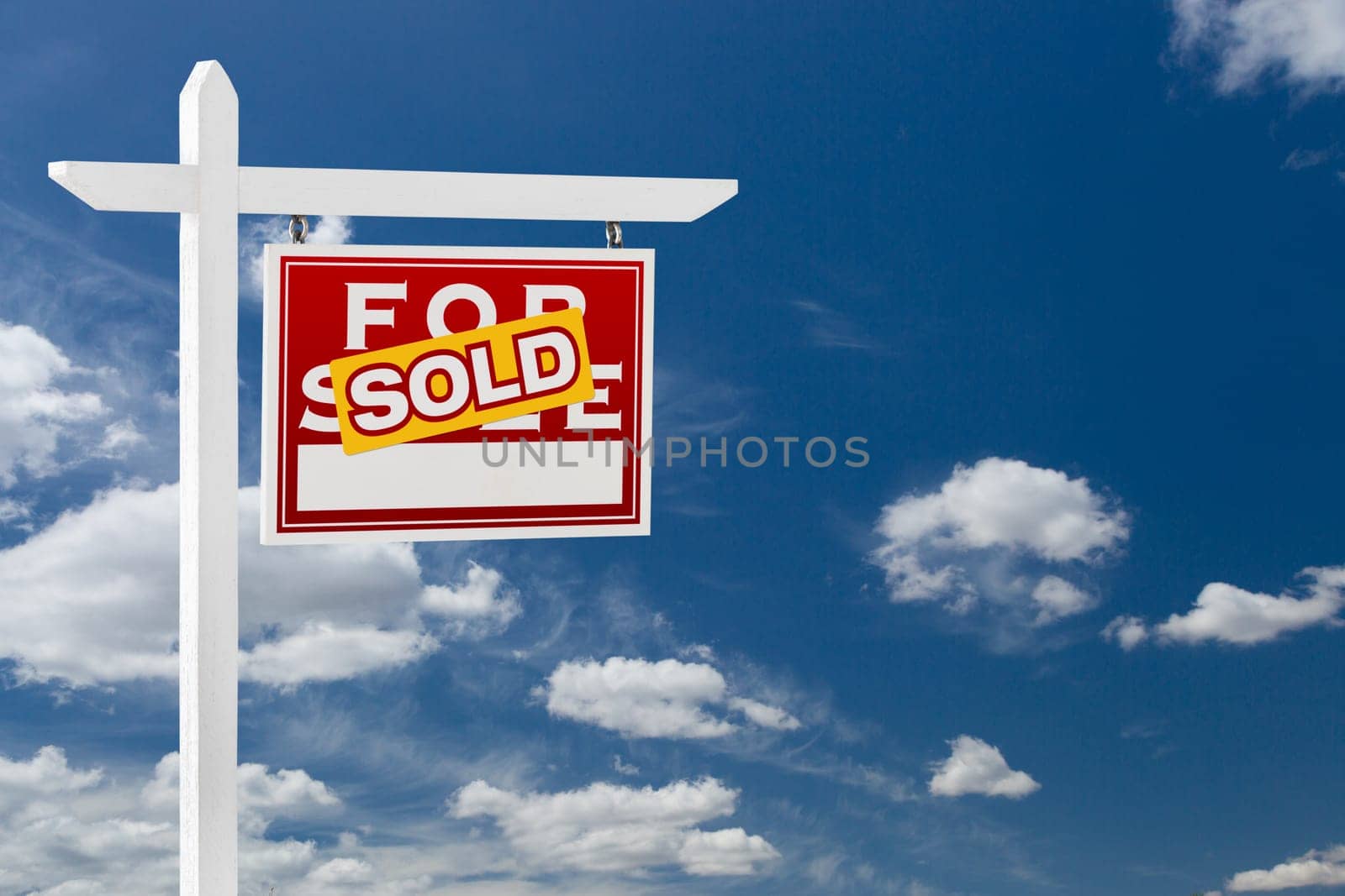 Right Facing Sold For Sale Real Estate Sign Over Blue Sky and Clouds With Room For Your Text.
