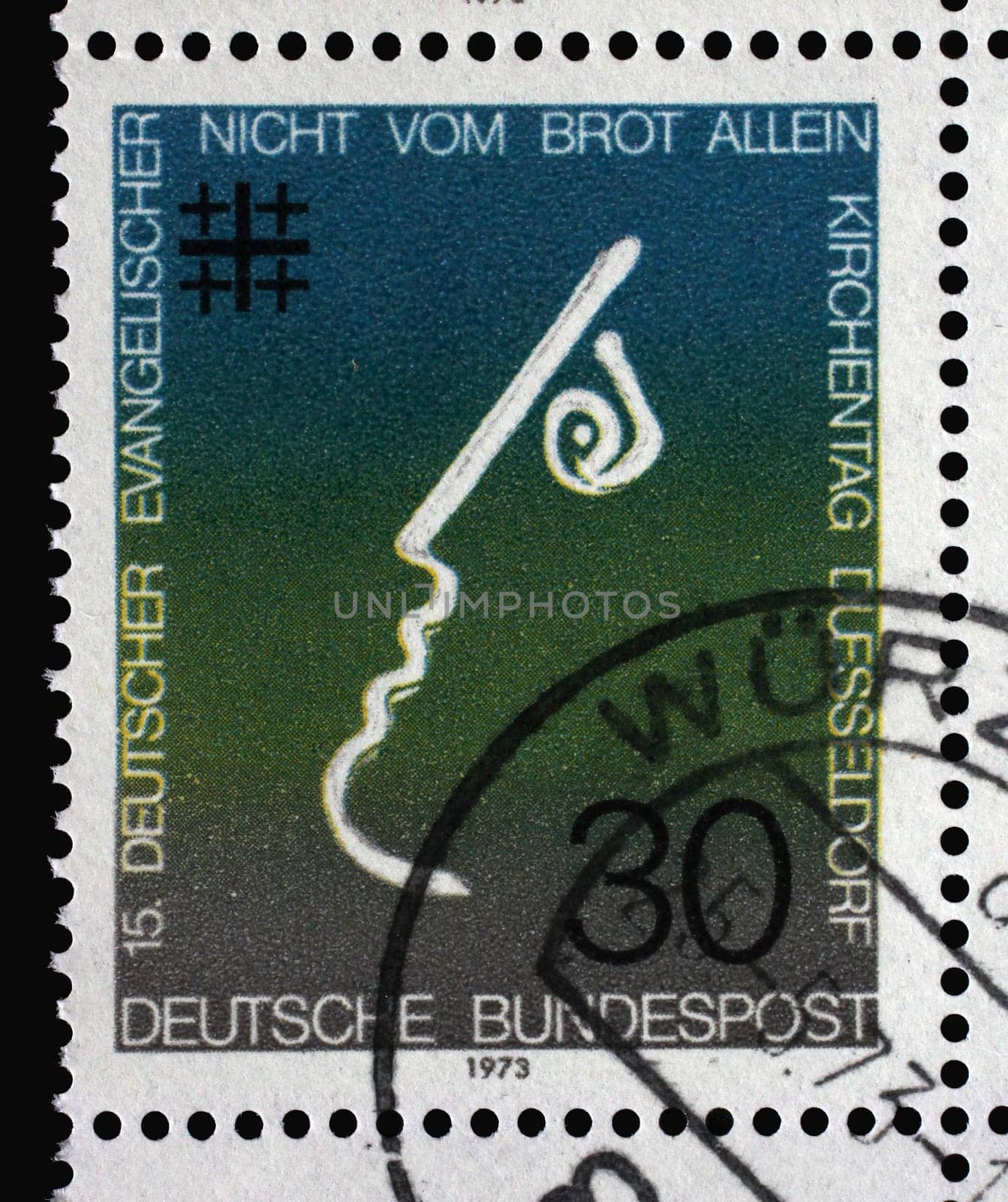 A stamp printed in Germany showing a stylized face and a cross symbol, Not by Bread alone, 15th meeting of German Protestants (Evangelical Synod) in Dusseldorf, circa 1973