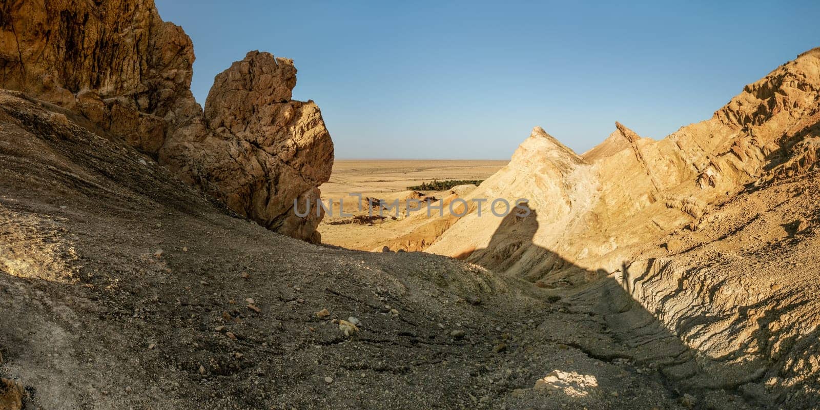Dry rocks near Chebika oasis with desert in background lit by midday sun. Atlas Mountains, Tunisia.