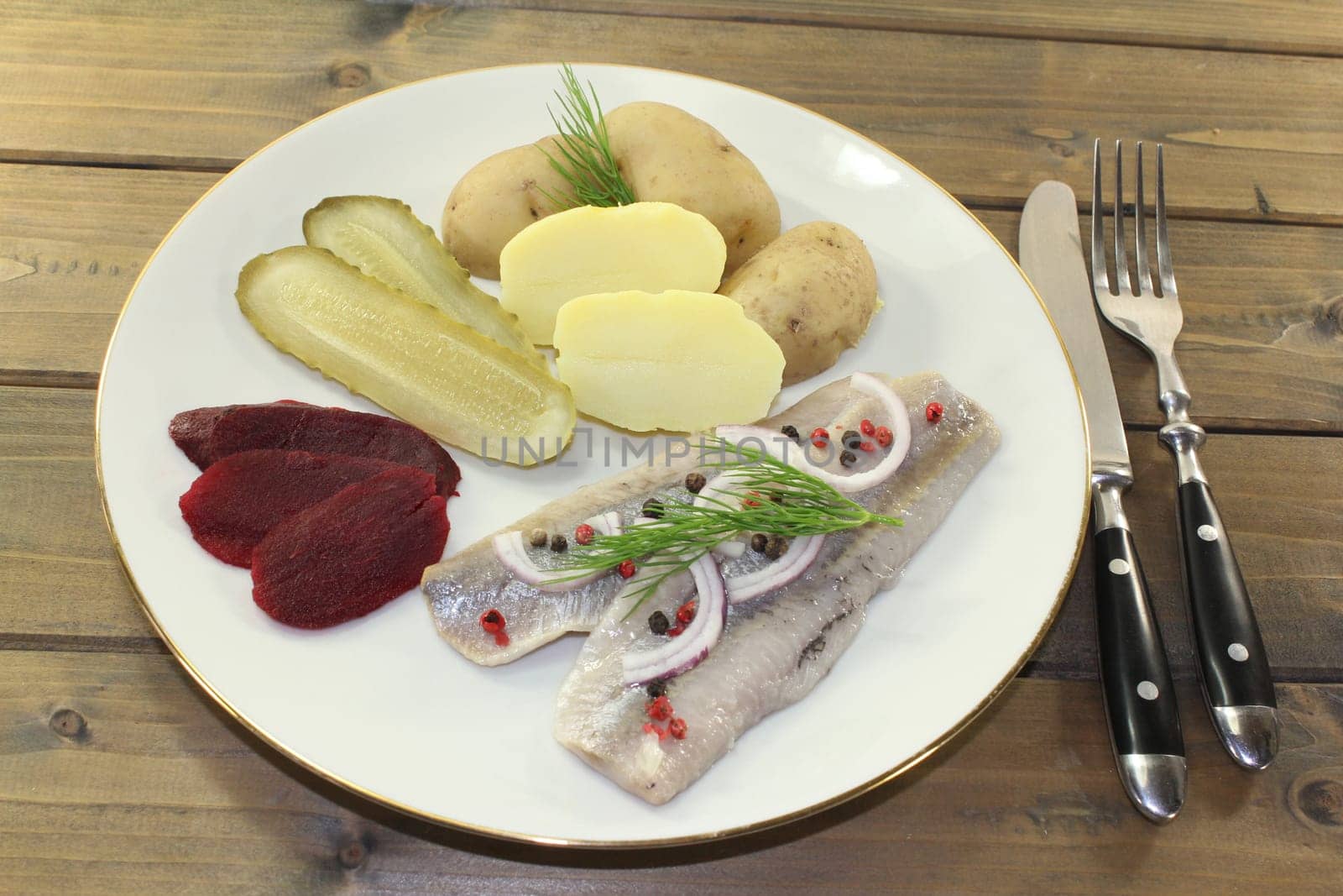 a plate of matjes fillet,peel potatoes,beetroot and sour cucumbers