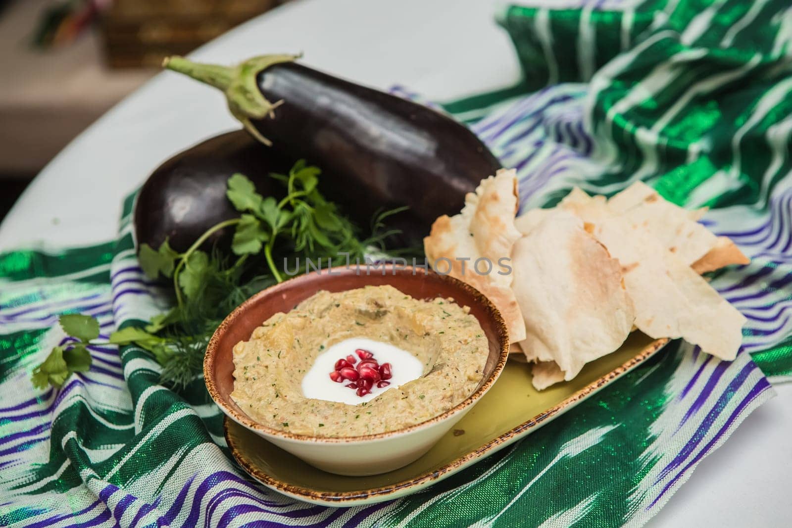 Traditional arabian eggplant dip baba ganoush with herbs and smoked paprika on a wooden background