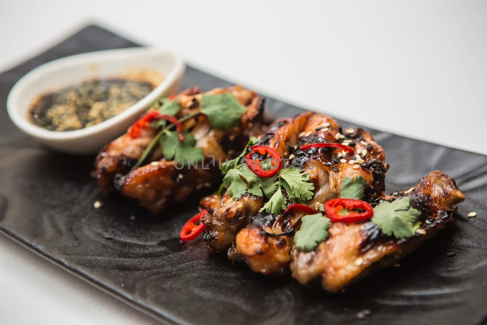 Hot organic chicken wings with red pepper on black dish