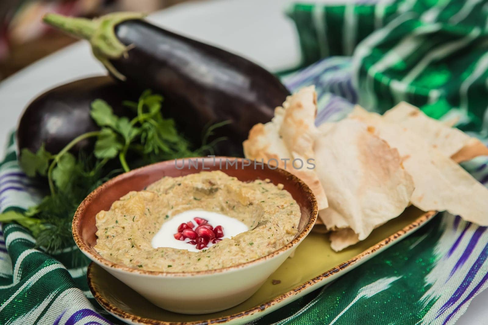 Traditional arabian eggplant dip baba ganoush with herbs and smoked paprika on a wooden background