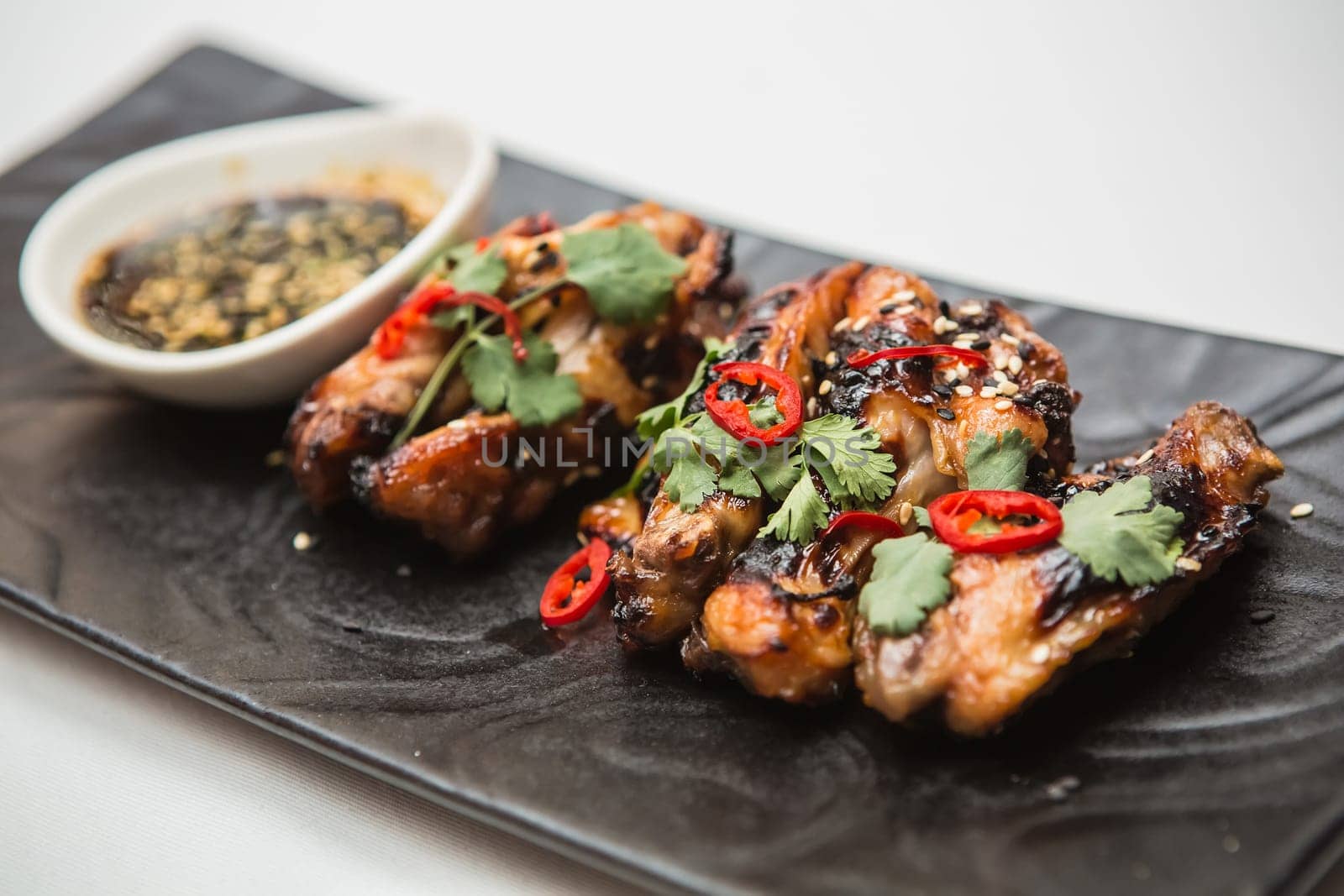 Hot organic chicken wings with red pepper on black dish