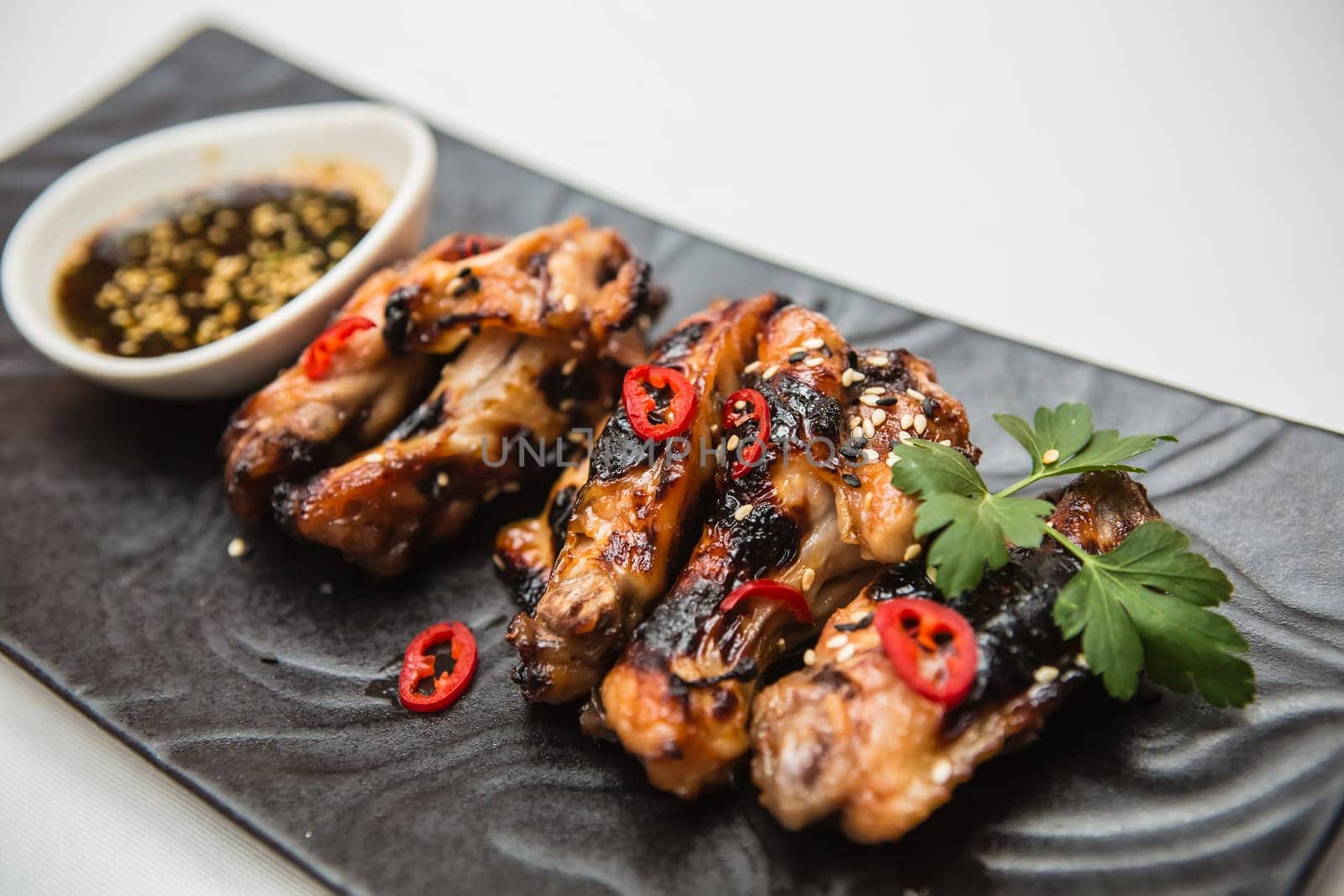 Hot organic chicken wings with red pepper on black dish