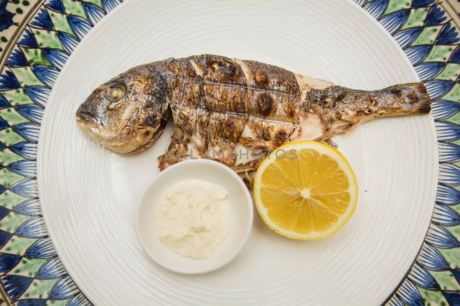 Grilled organic dorada fish with lemon on white dish