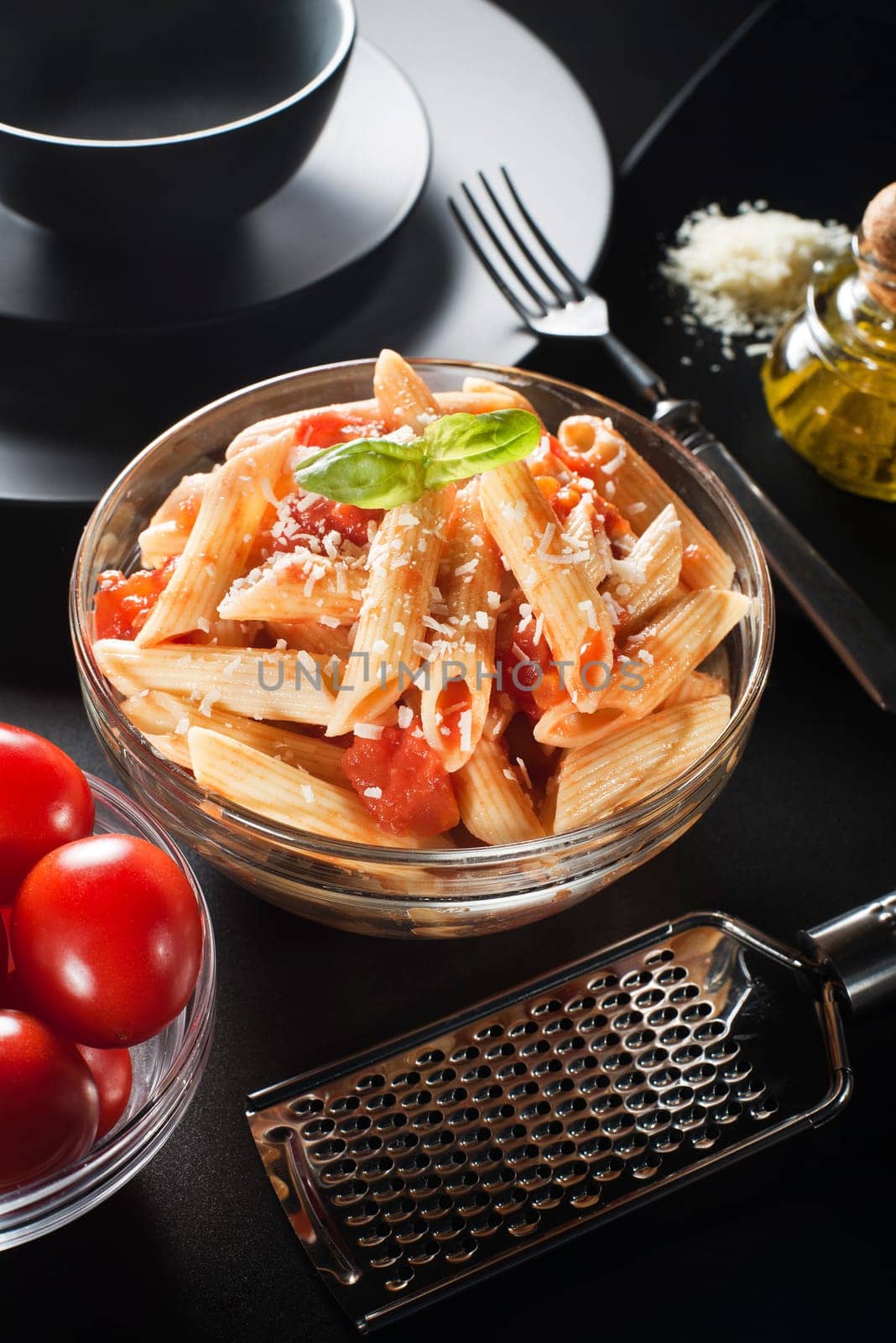 Penne pasta with tomatoes sauce and parmesan on black background
