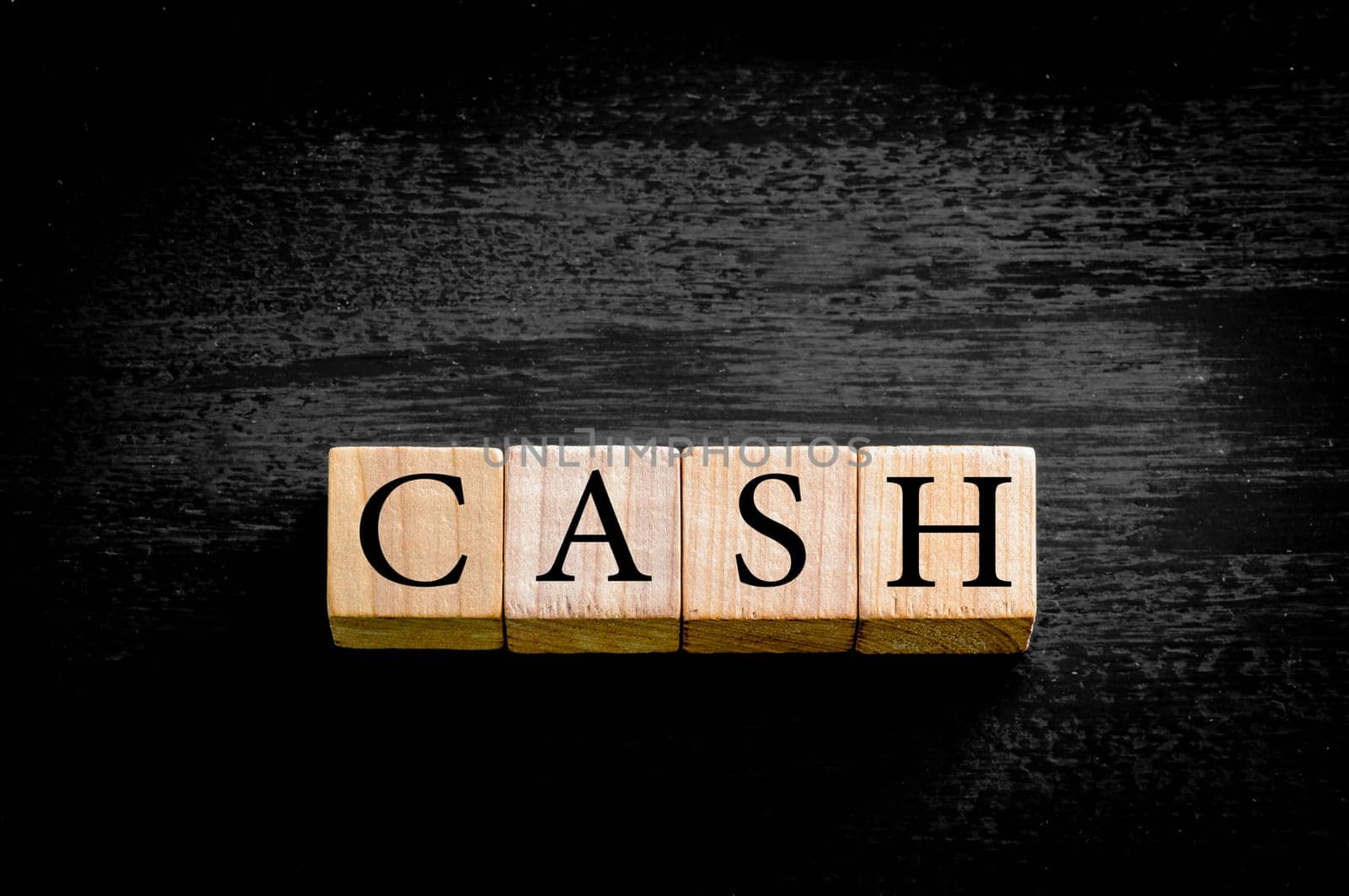 Word CASH. Wooden small cubes with letters isolated on black background with copy space available. Concept image.