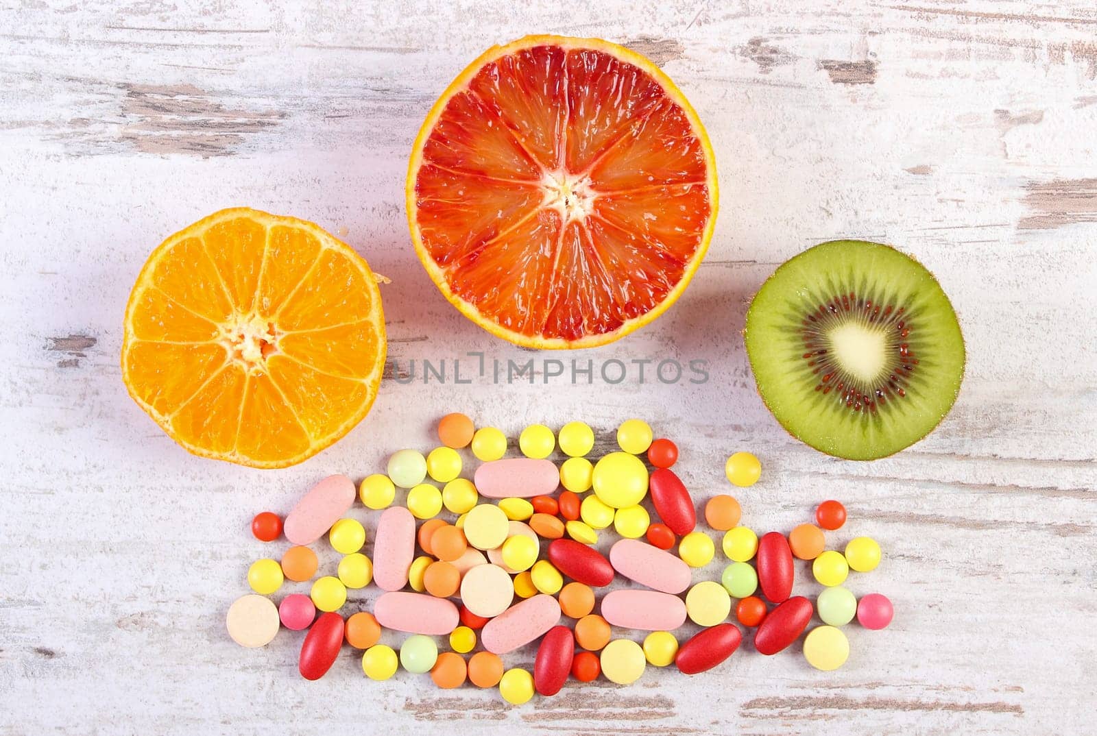 Fresh natural fruits and medical pills, tablets and capsules on rustic wooden background, choice between healthy nutrition and medical supplements, healthy lifestyle