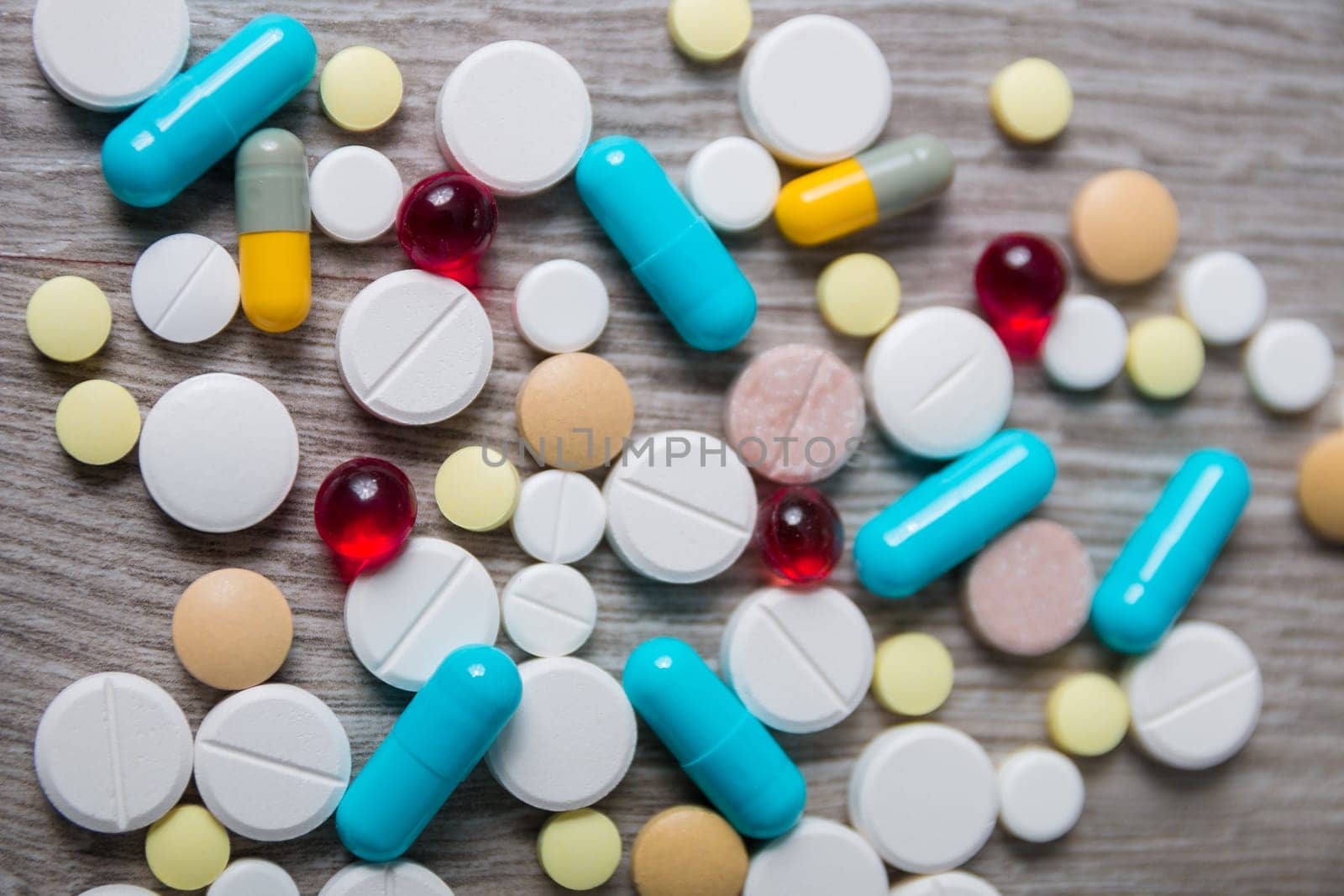 A lot of colorful medication and pills from above on grey wooden background. Copy space. Top view, frame. Painkillers, tablets, generic pills, drugs.