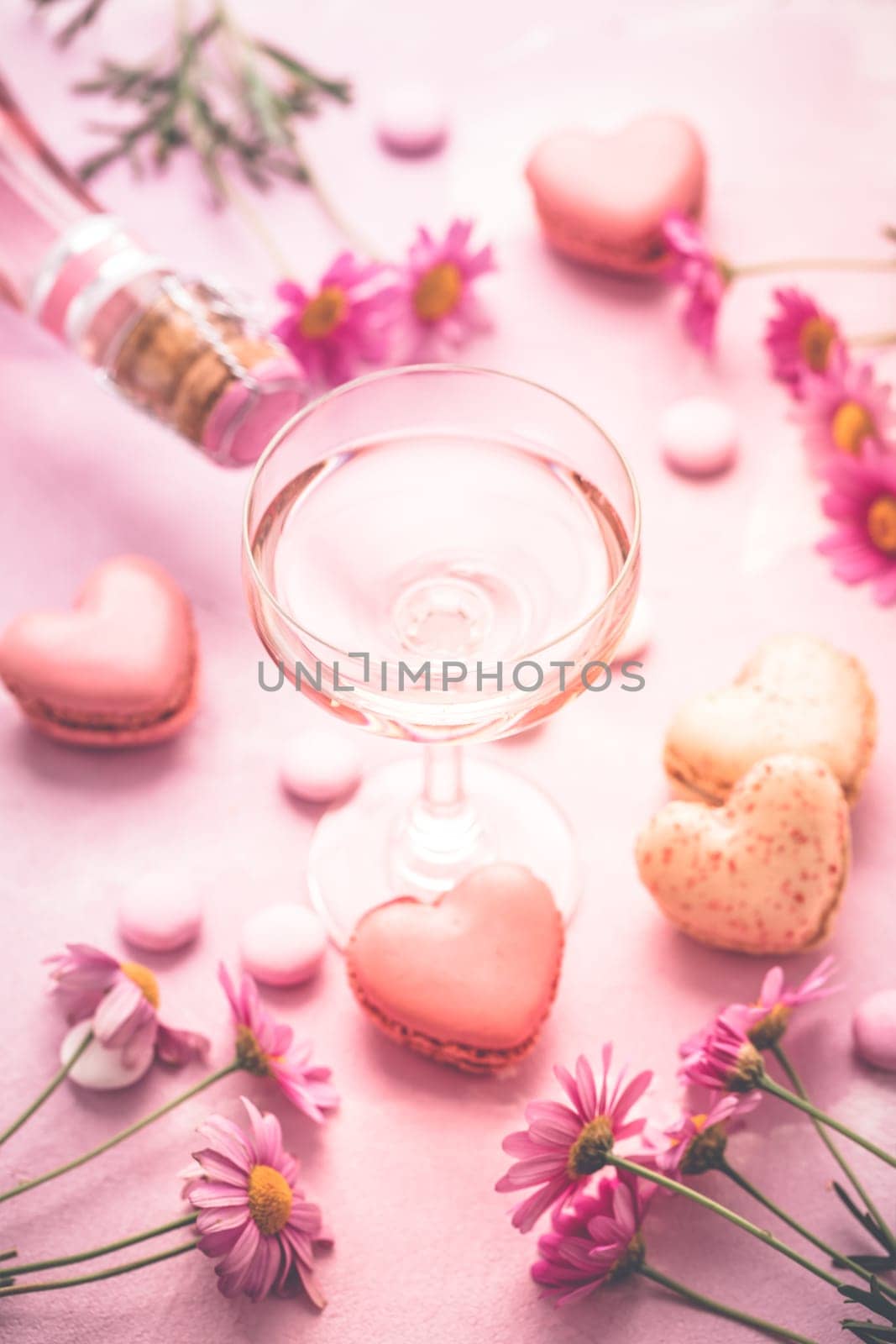 Happy Mothers Day - sweet macarons in heart shape and glass of rose sparkling wine with flowers in pink tone