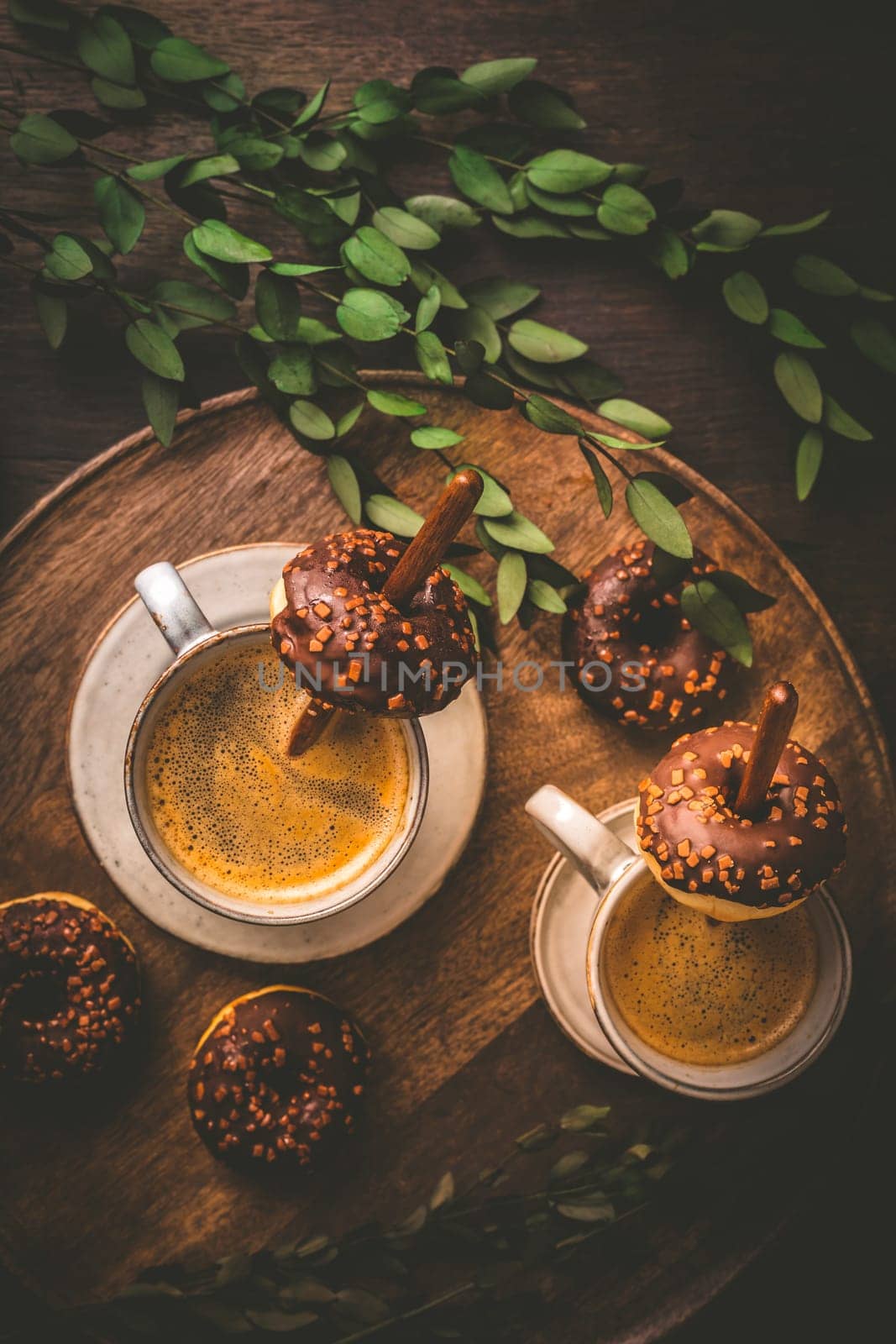 Coffee time - two cups of Caffe Americano with small chocolate donuts