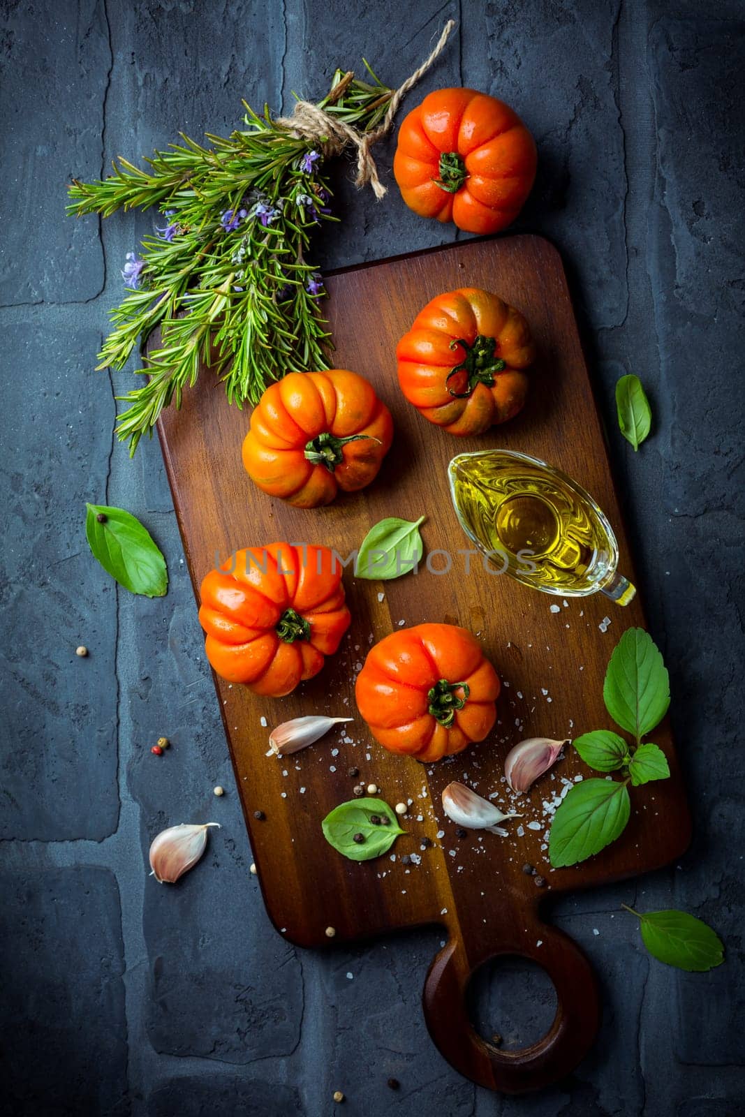 Italian cuisine - Olive oil, tomato and herbs on rustic cutting board