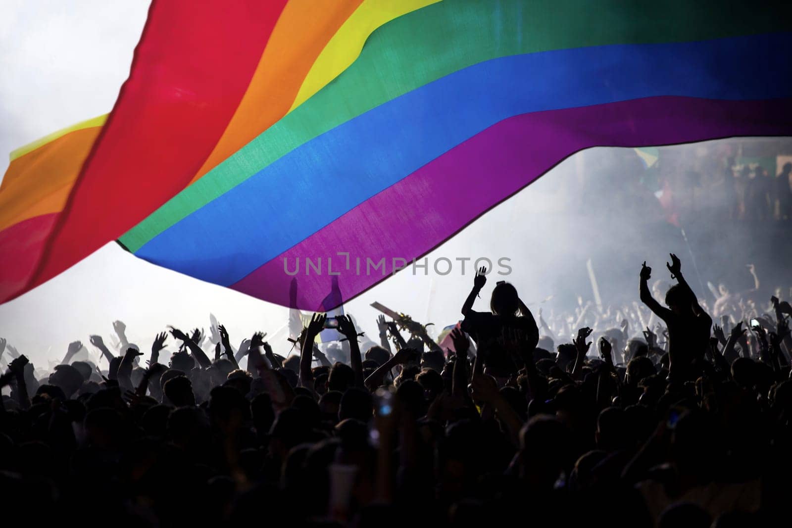 Pride community at a parade with hands raised and the LGBT flag - symbol of love and tolerance