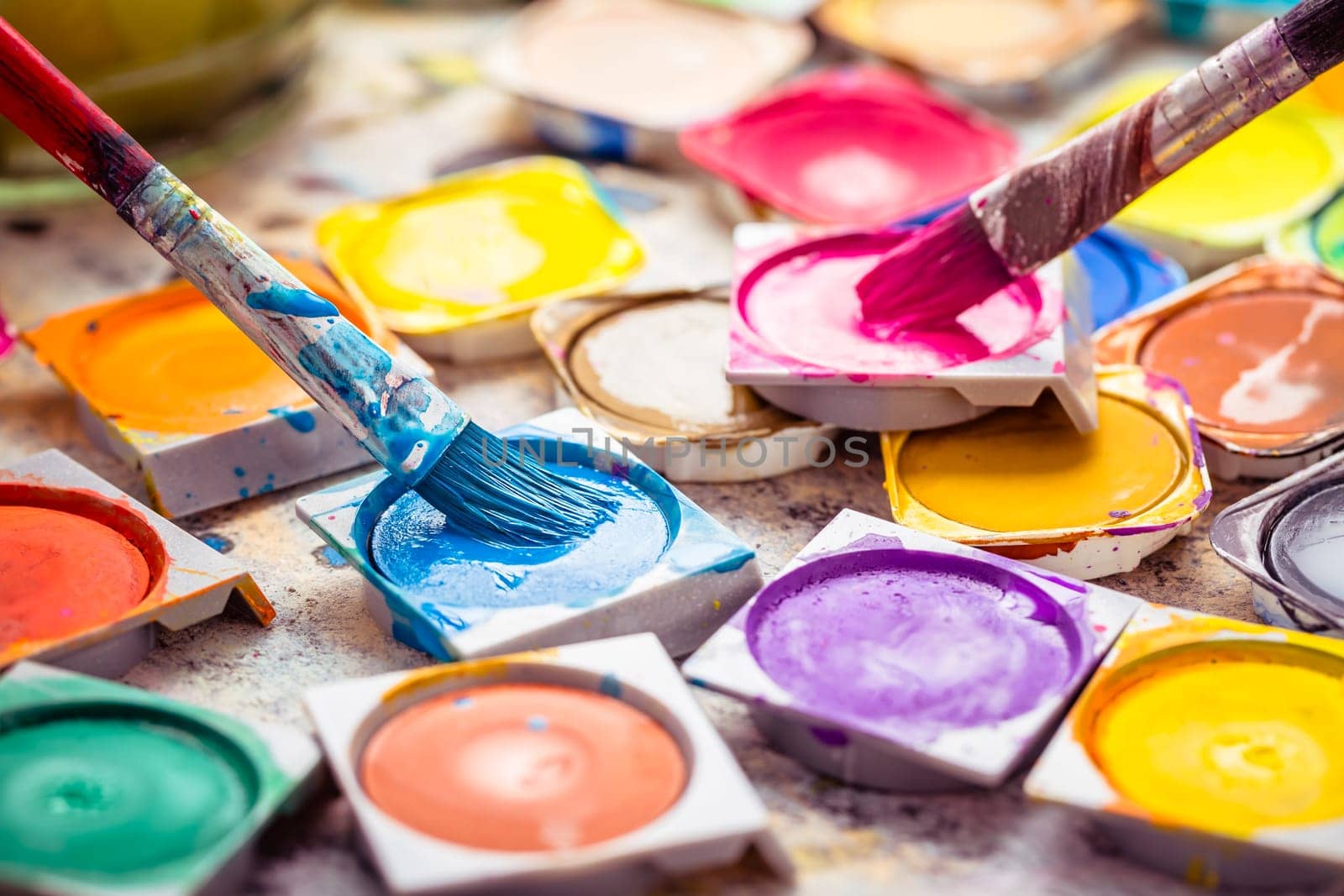 Set of colorful watercolor paints and paintbrushes for painting closeup. Selective focus.