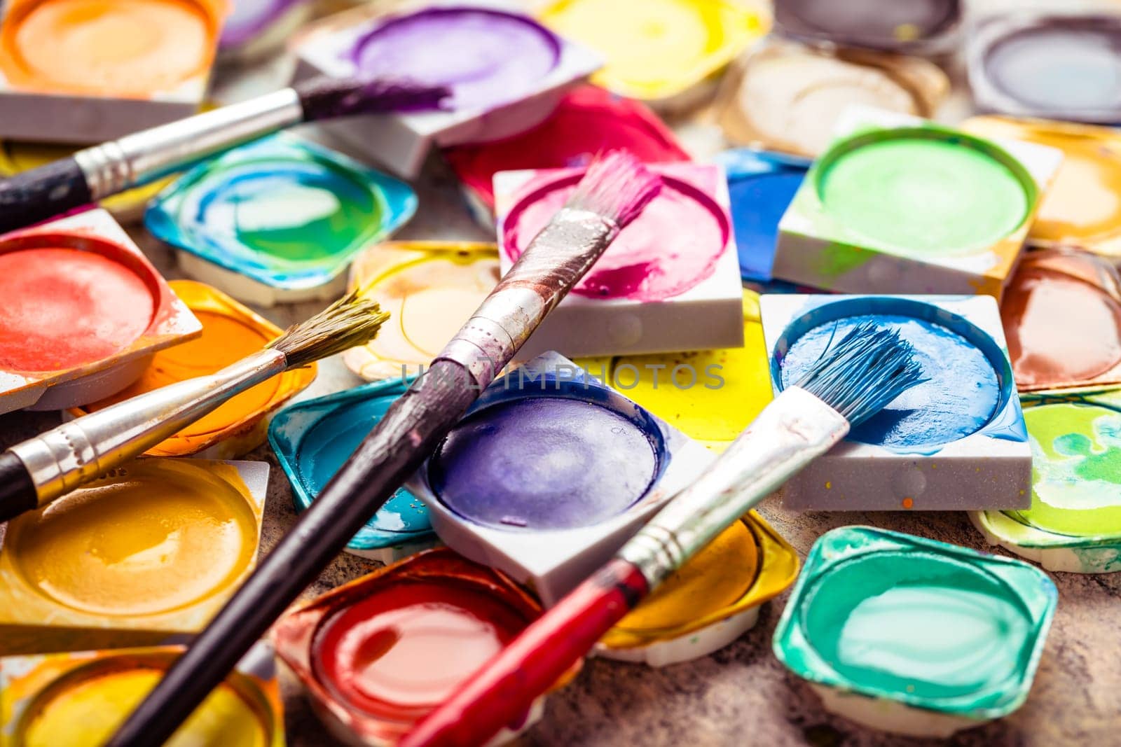 Set of colorful watercolor paints and paintbrushes for painting closeup. Selective focus.
