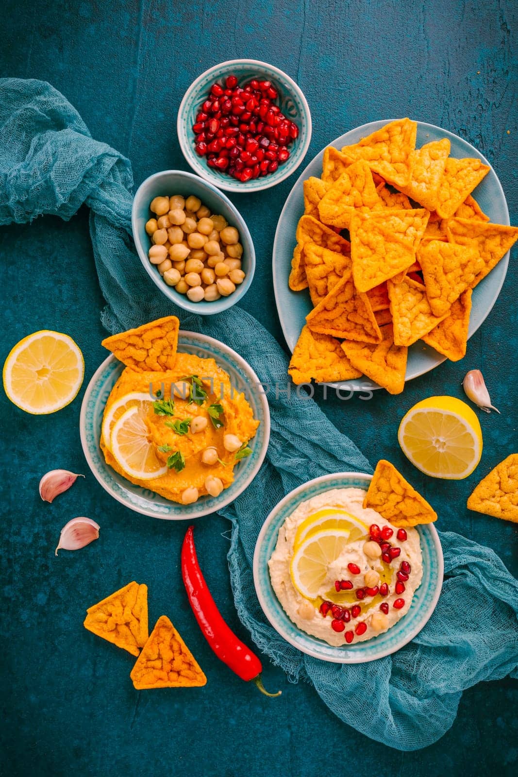Homemade spicy humus with pomegranate seeds, chilli and chickpeas tortilla chips