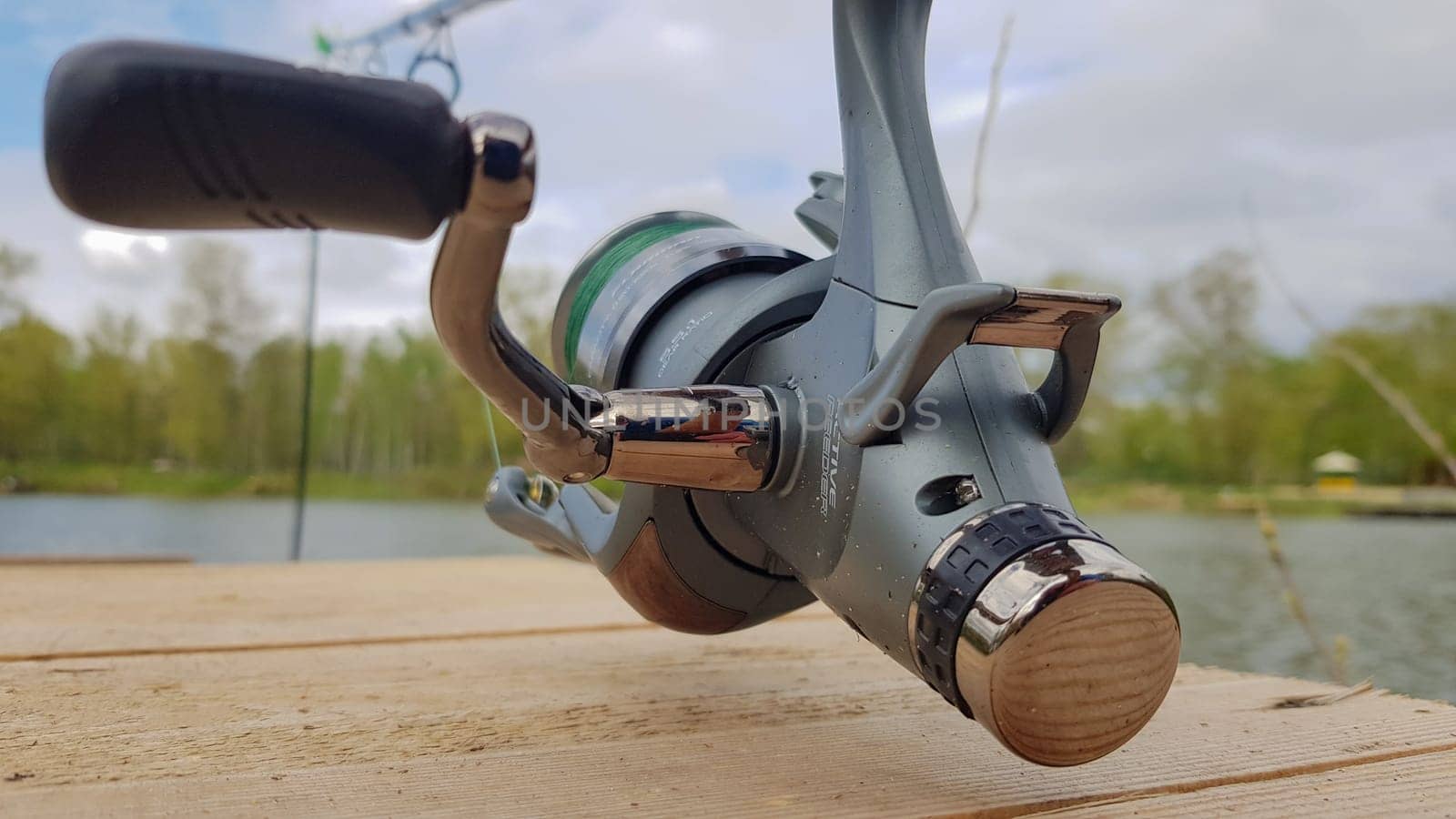 Carp fishing rod isolated on the lake and wooden bridge. Carp feeder spinning reel close up. Fishing for carp on the lake. Fisherman's equipment. Ukraine, Kiev - June 09, 2021