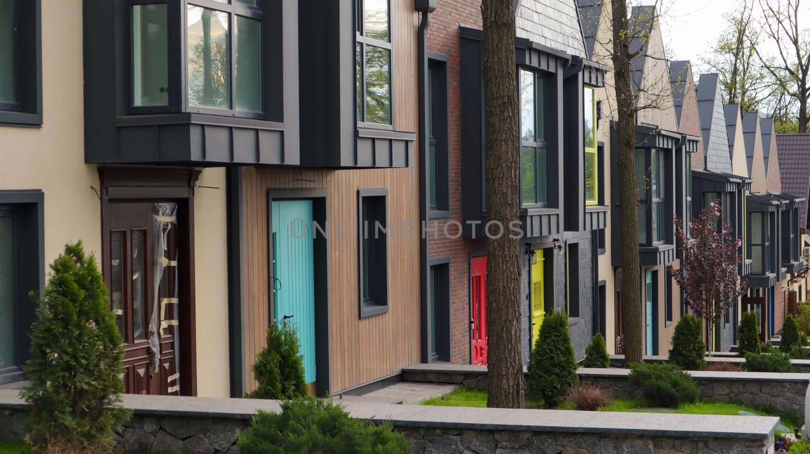 A street with houses and manicured lawns in a typical suburb. Frame made of small brown brick American country houses. Ukraine, Irpin - 07 June 2021