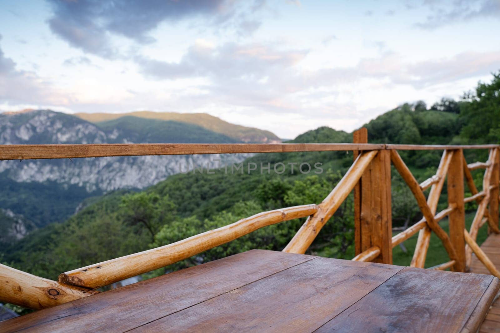 panorama of wooden table on deck and fence with mountain range scenery