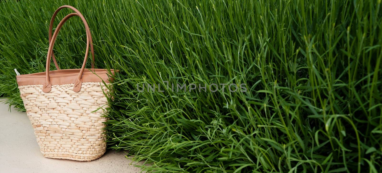 front view closeup of empty brown wicker bag with green grass in the background