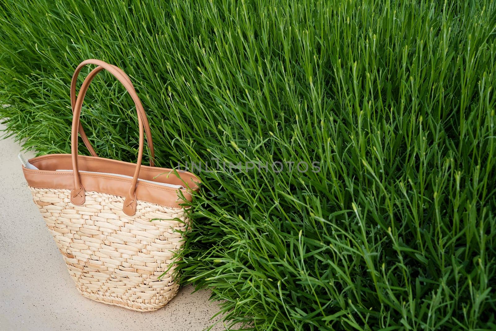 front view closeup of empty brown wicker bag with green grass in the background