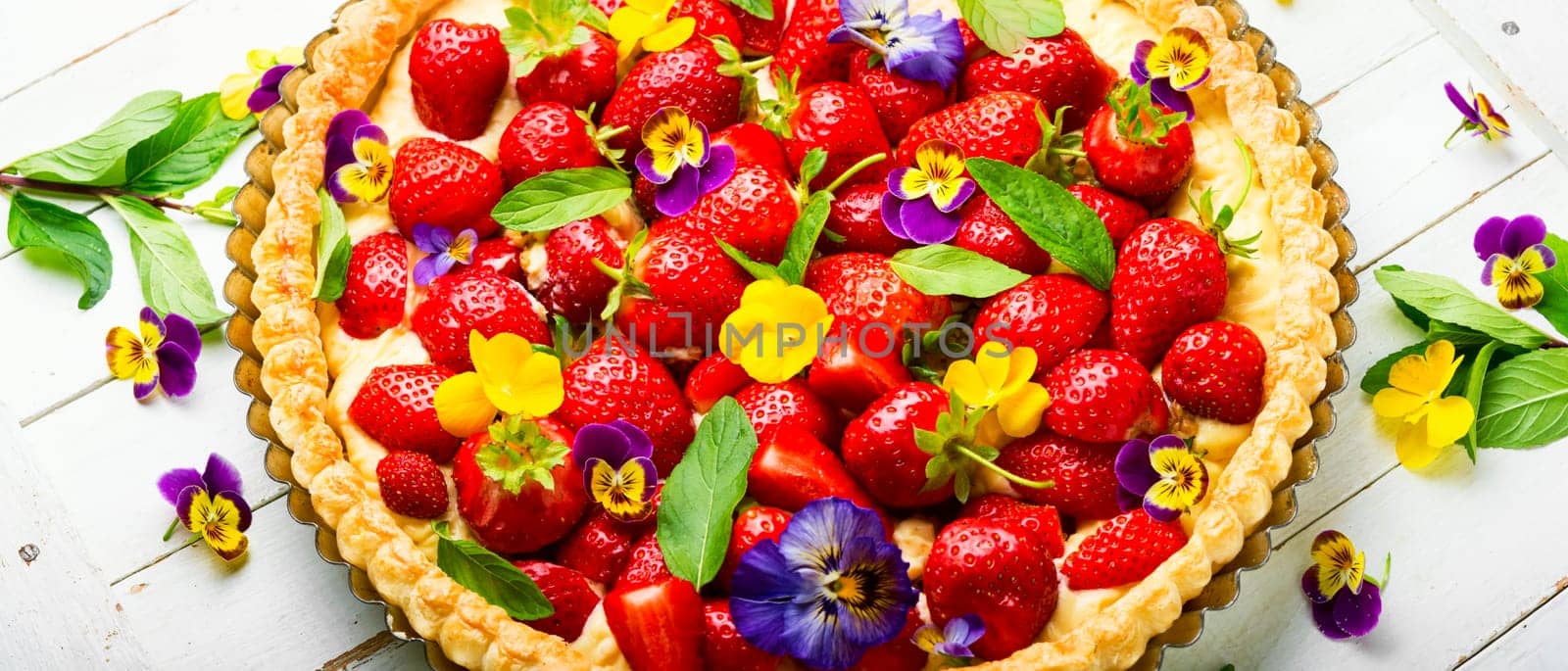 Summer tart with strawberries.Pie decorated with mint and flowers on rustic wooden background