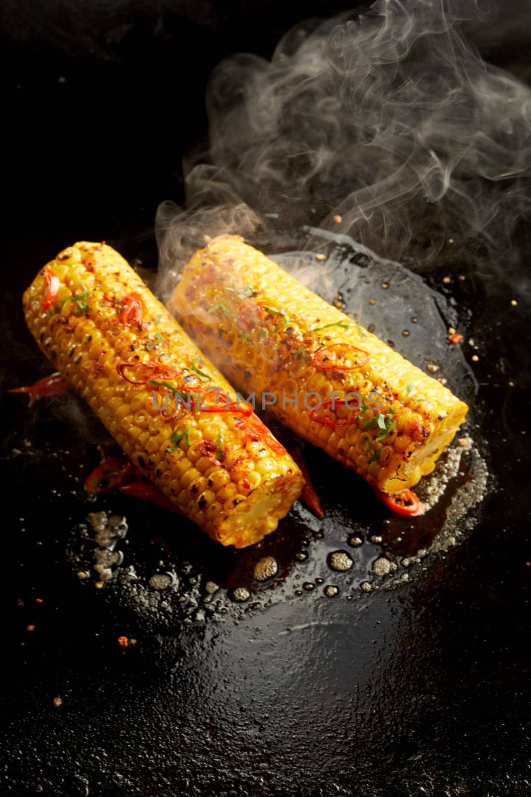 Top view of palatable corn cooking in oil on black surface in kitchen