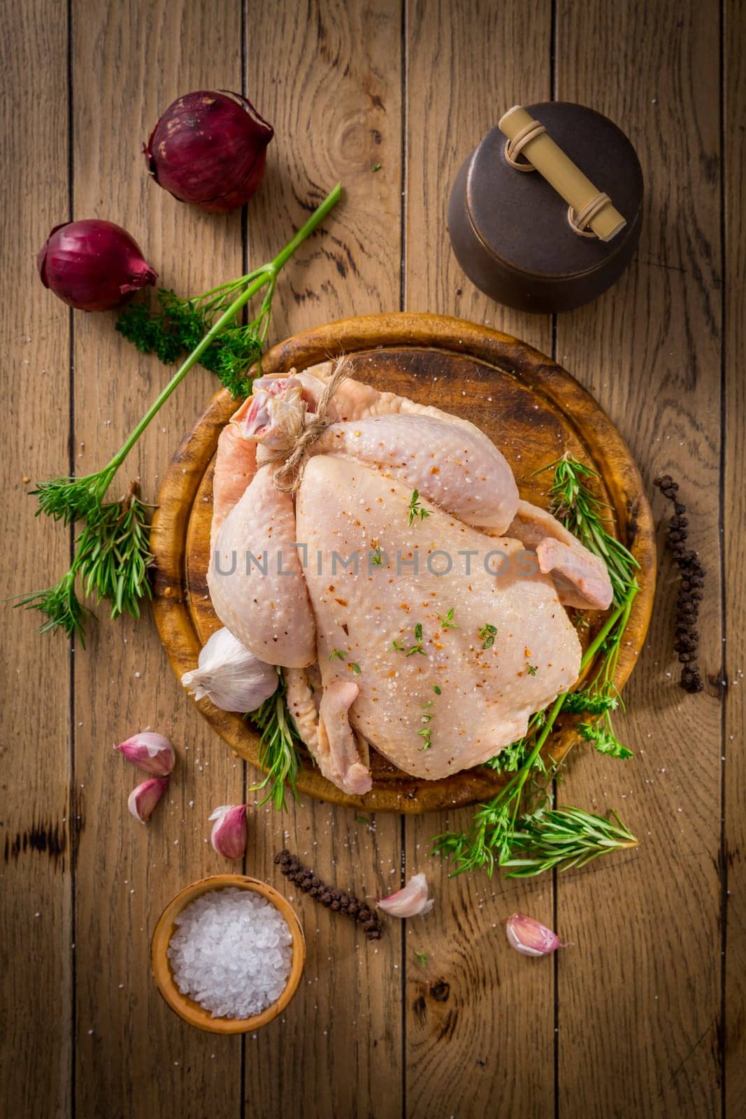 Raw chicken with onion, garlic and herbs with spices ready for cooking on wooden table