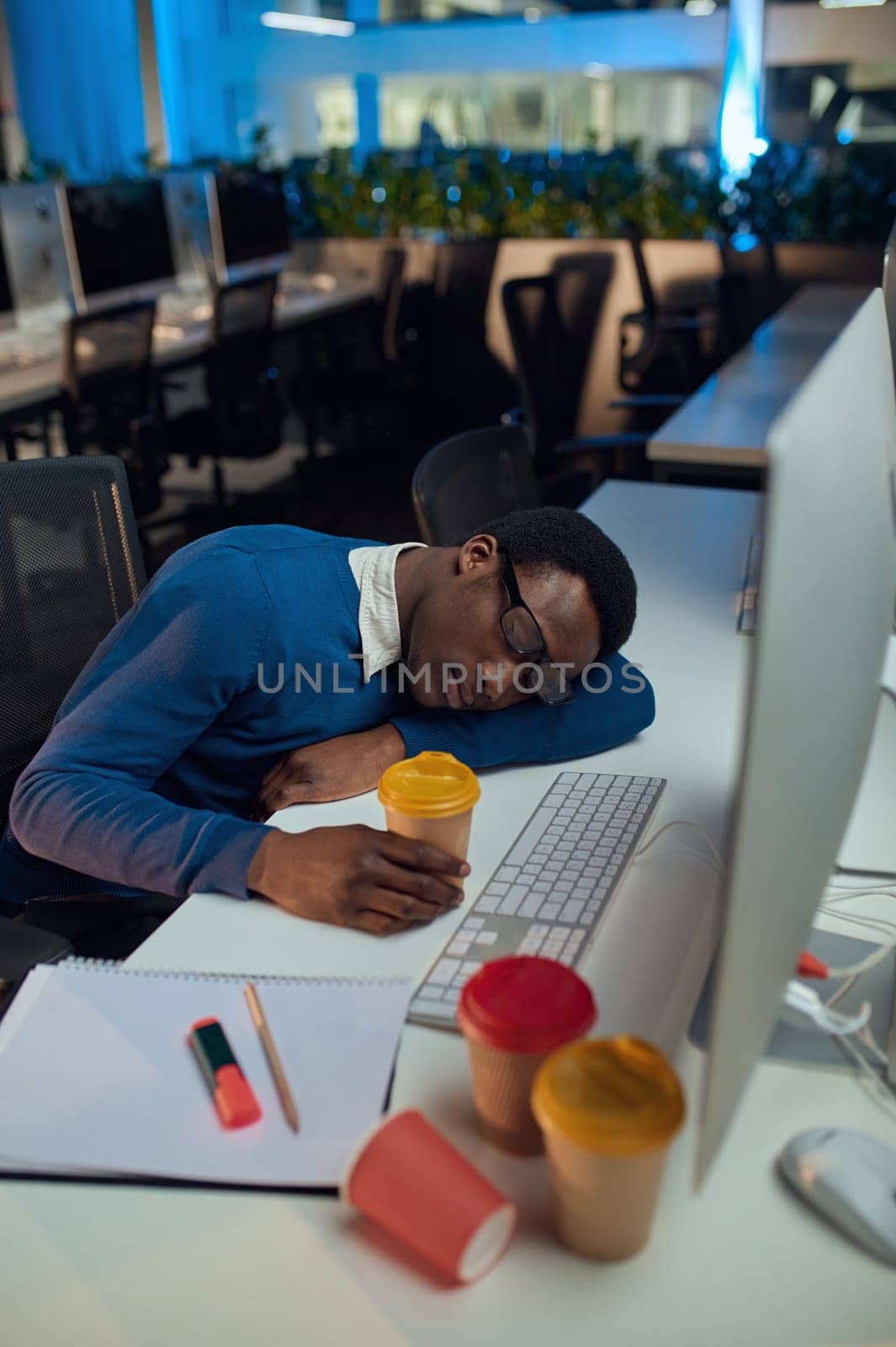 Manager sleeping at the table, night office lifestyle. Male person at laptop, dark interior on background, modern workplace