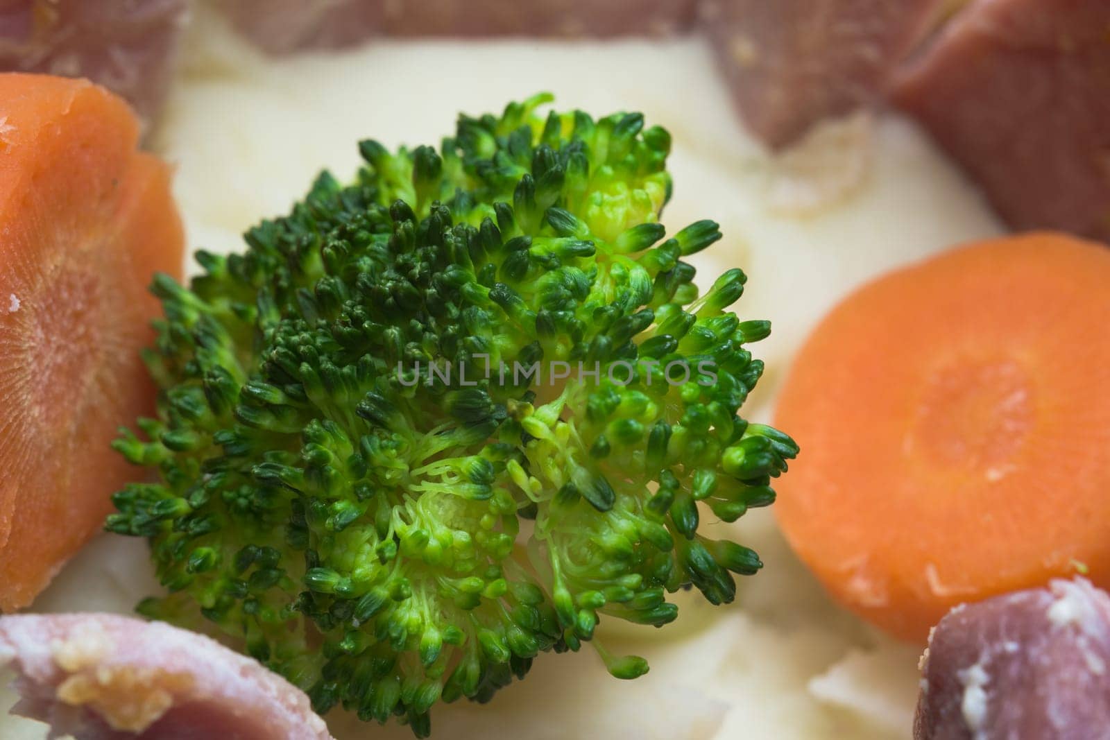 Full frame close up of cooked food, broccoli central, gammon meat, other vegetables and mashed potato carbohydrate surround. Balanced dinner meal.