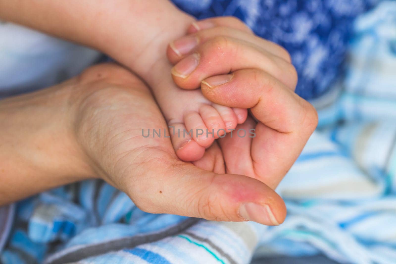 Close up of mother’s hands, holding newborn baby feet.