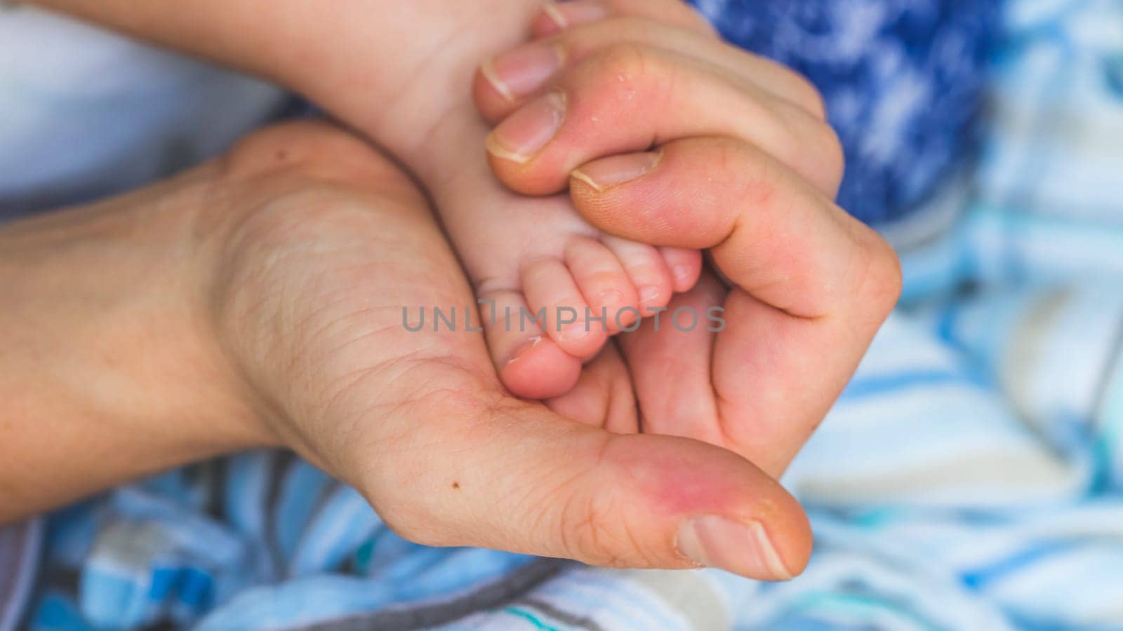 Close up of mother’s hands, holding newborn baby feet.