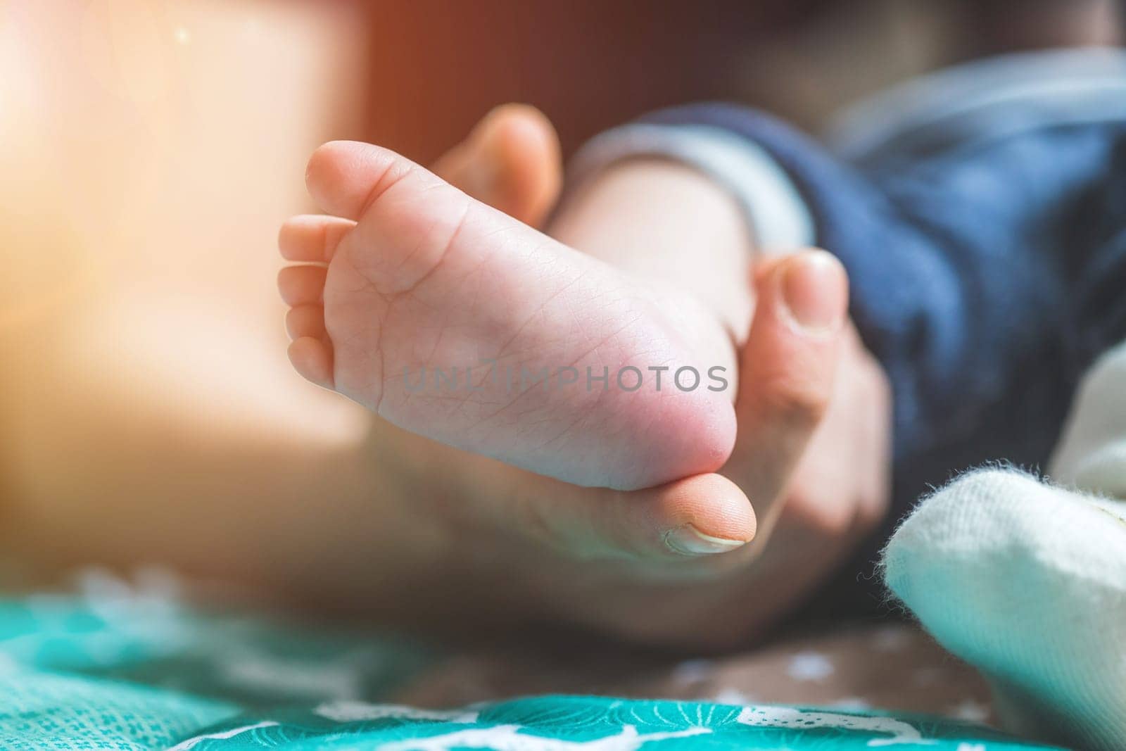 Close up of mother’s hands, holding newborn baby feet.