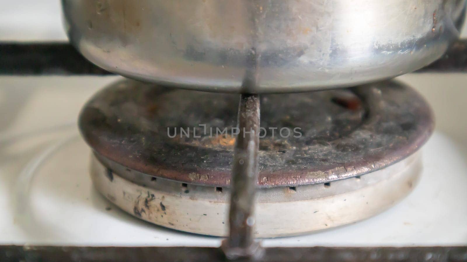 Dirty gas stove in the kitchen for cooking with vegetable oil stains and burnt food debris on the surface, close-up. Selective focus. Grease-covered gas hob in the kitchen