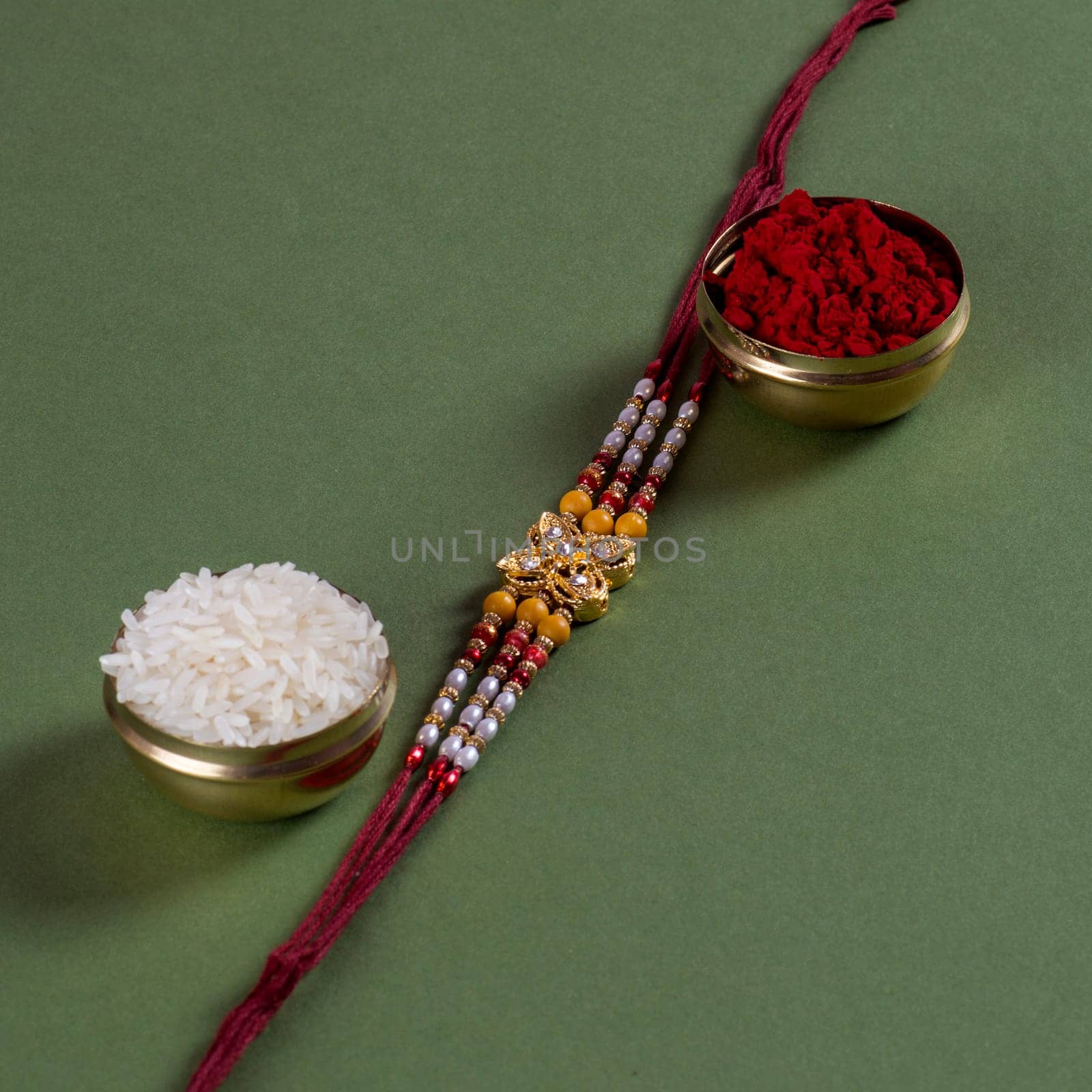 Indian festival: Raksha Bandhan background with an elegant Rakhi, Rice Grains and Kumkum. A traditional Indian wrist band which is a symbol of love between Brothers and Sisters.