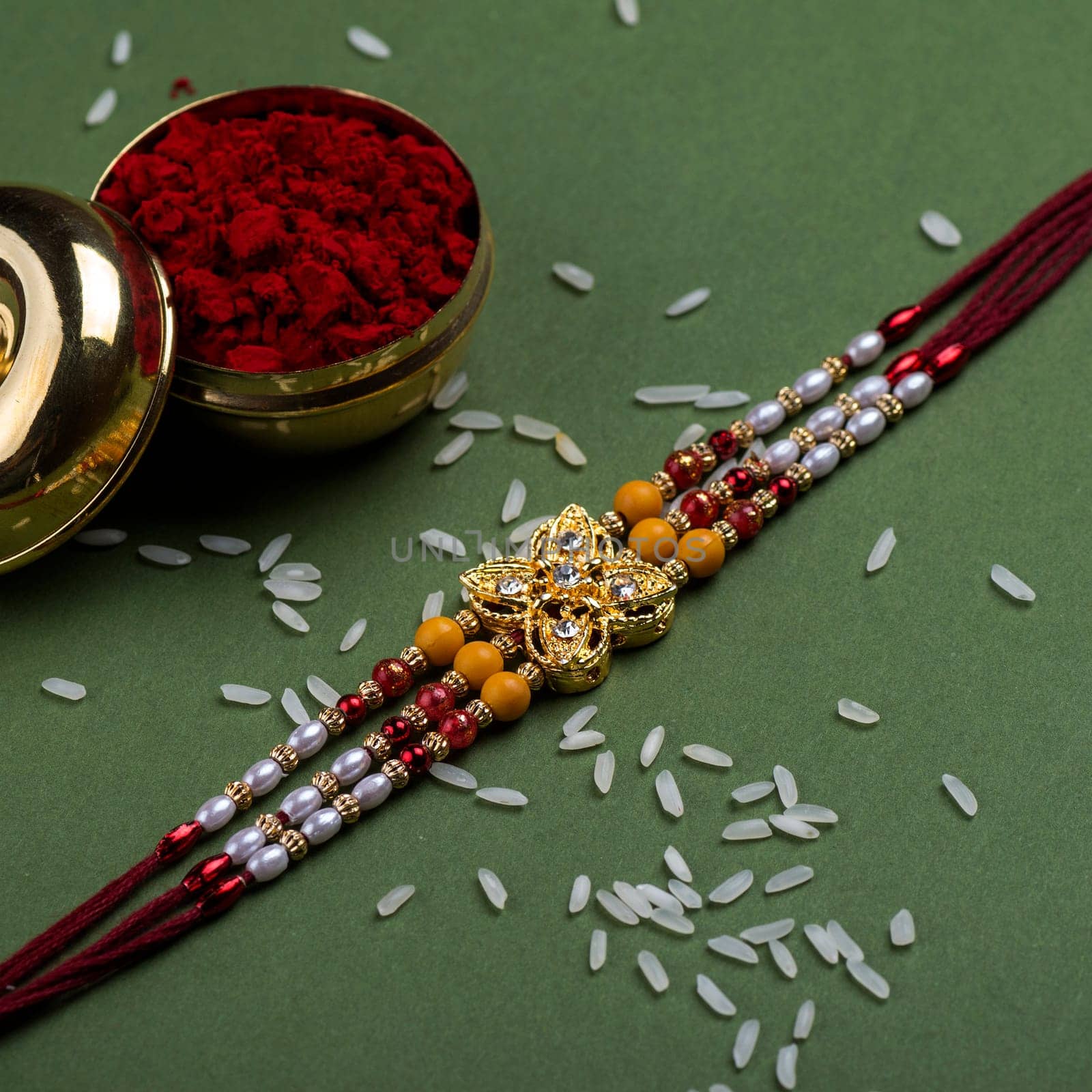 Indian festival: Raksha Bandhan background with an elegant Rakhi, Rice Grains and Kumkum. A traditional Indian wrist band which is a symbol of love between Brothers and Sisters.