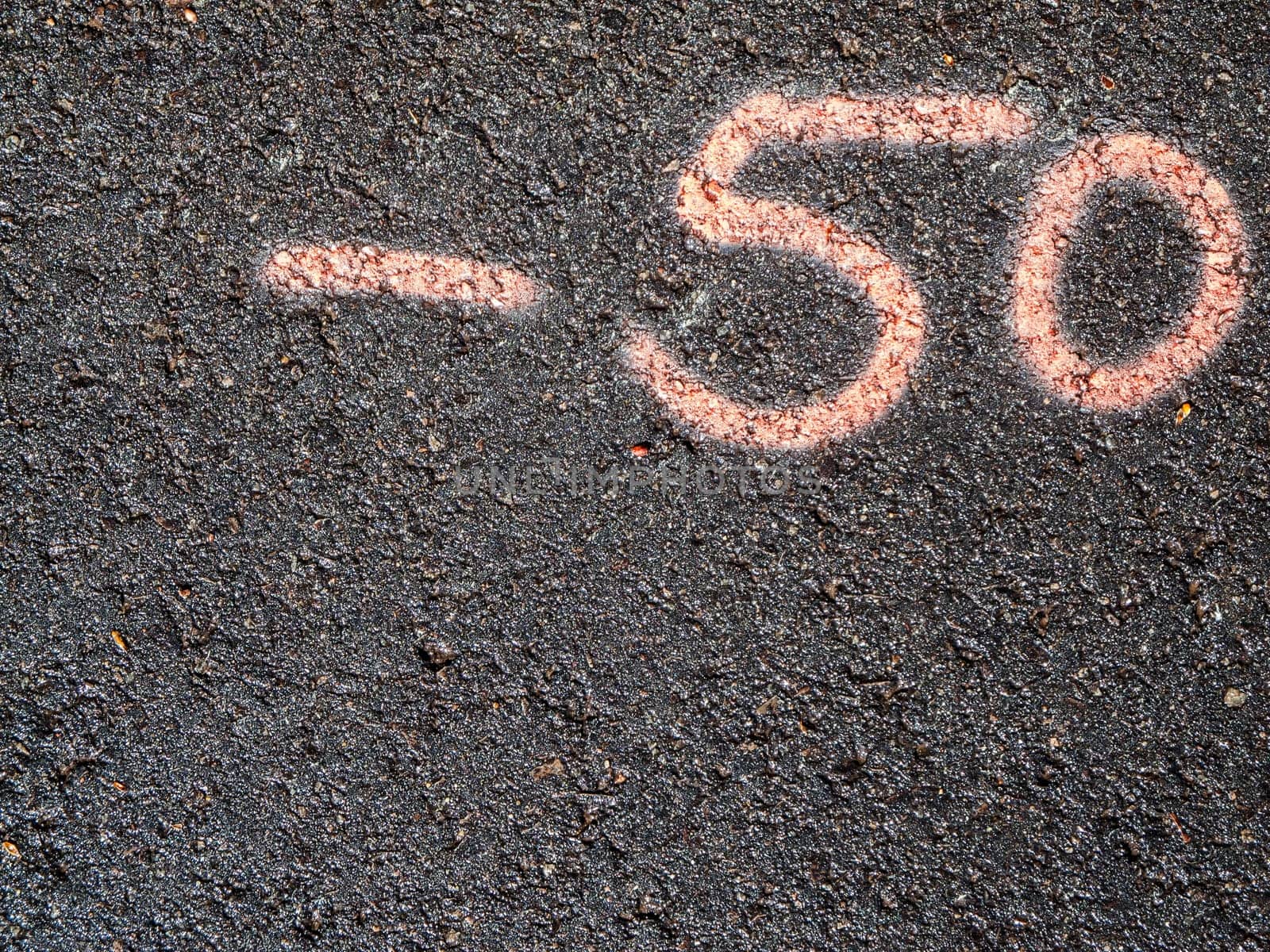 Top view of number minus 50 written on asphalt in pink color.