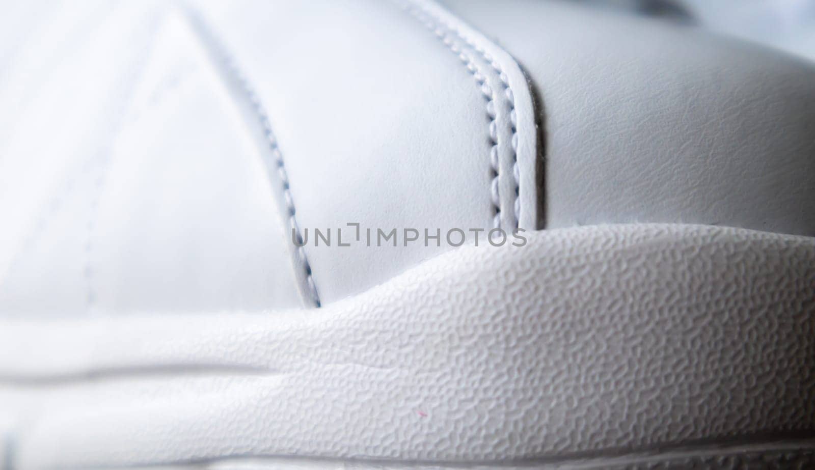 Close up low angle view of the outsole of the front of the new white sneakers. Rubber sole on the toe of men's shoes. Sole for sports and walking shoes. Material texture of sports shoes