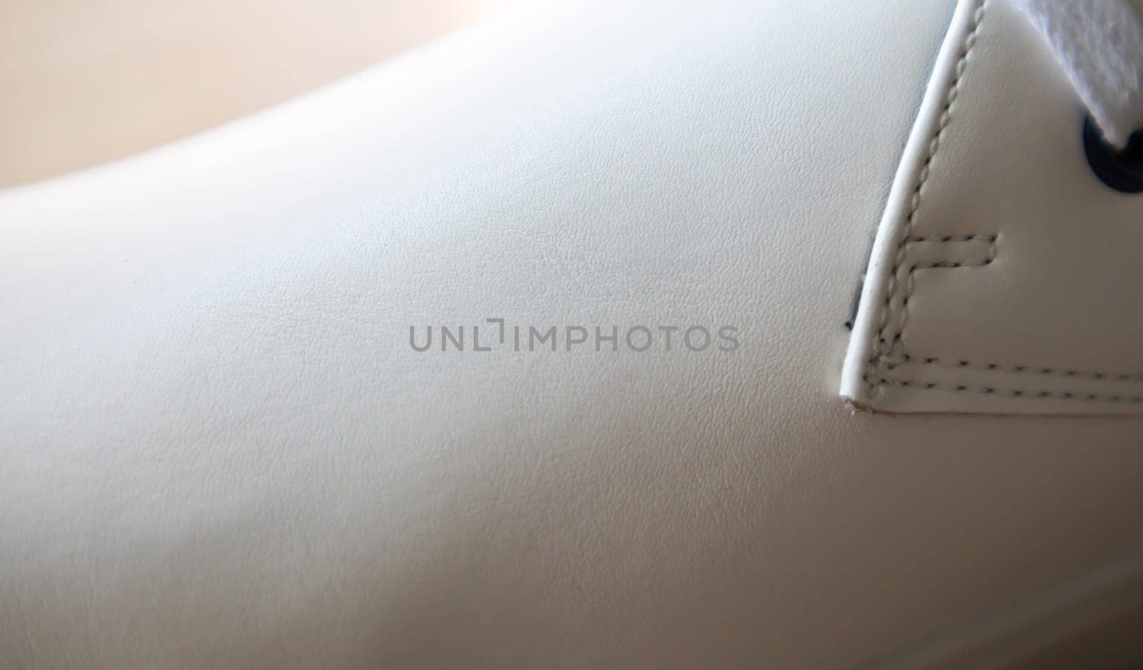 White leather sneakers lace-up shoes. White laces are tied close-up. Blurred background. Sports concept. Metal rivet for shoes as a detail or an element. Fashionable and stylish footwear