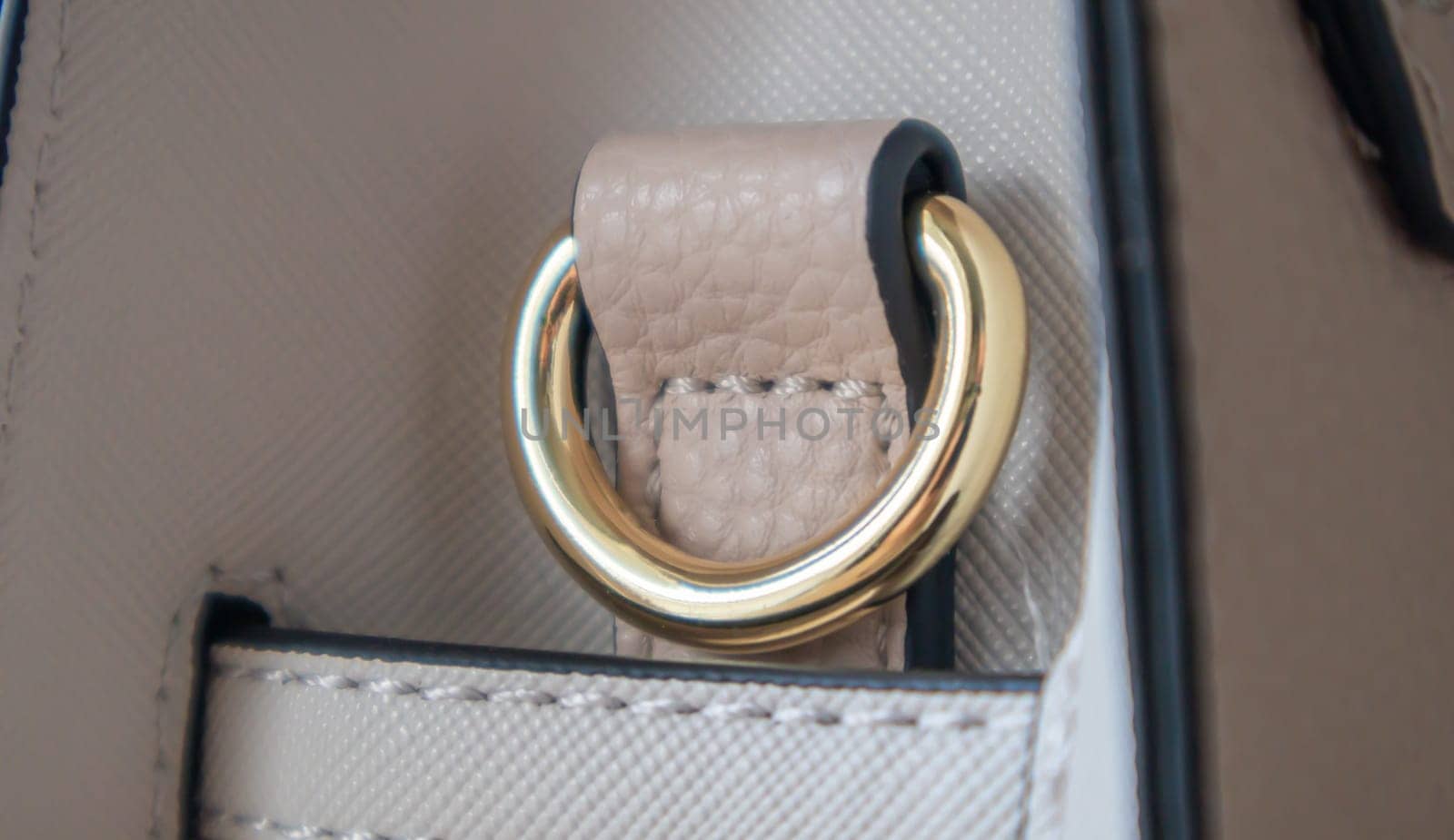 Metal gold loop oval ring attached to a leather bag. Selective focus. Part for a secure connection between two objects. Sewing accessories in the form of a ring for sewing bags, glossy