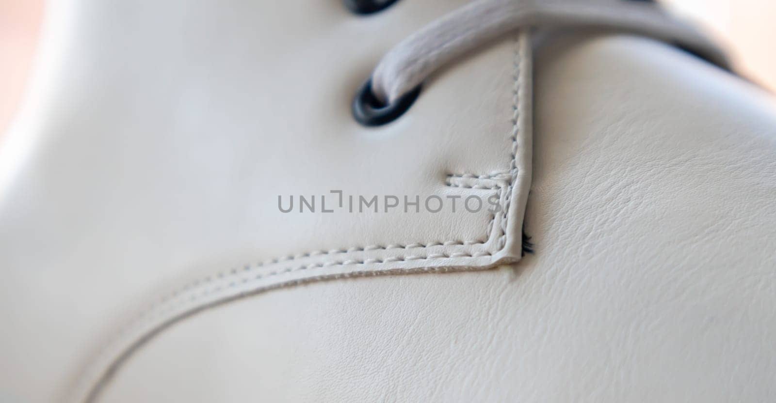 White leather sneakers lace-up shoes. White laces are tied close-up. Blurred background. Sports concept. Metal rivet for shoes as a detail or an element. Fashionable and stylish footwear