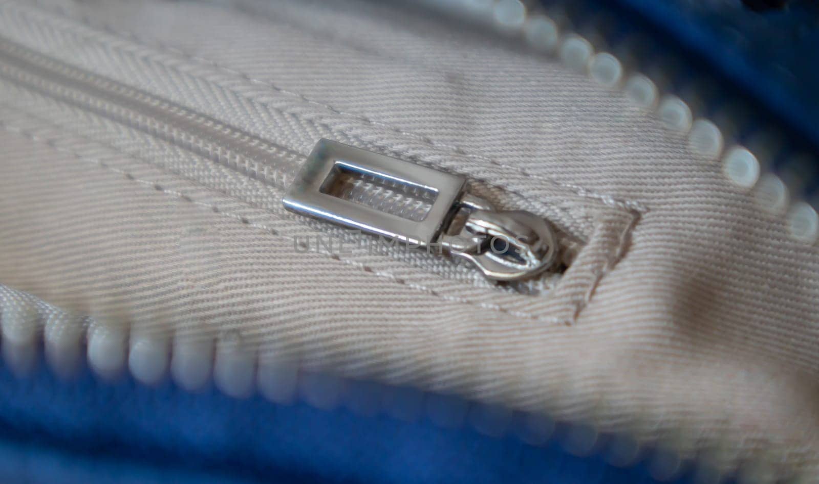 Natural or artificial leather texture. Fragment of a blue bag with a zipper and stitching. Zipper or clasp bag design element. Bovine skin texture with snake. Macro photo, selective focus