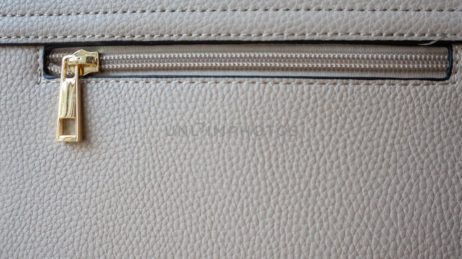 Natural or artificial leather texture. Fragment of a beige or powdery bag with a zipper and stitching. Zipper or clasp bag design element. Bovine skin texture with snake. Macro photo, selective focus