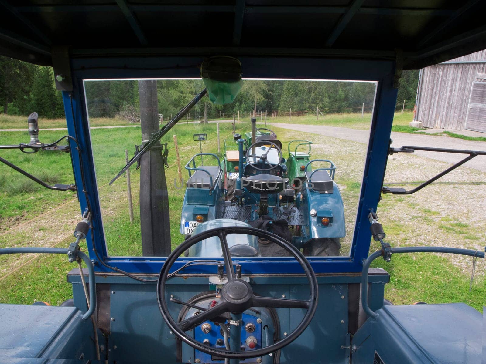 Nesselwang, Germany - July 23, 2020: Interior view with a view through the windshield of a green restored LANZ tractor aside from a veteran tractor.