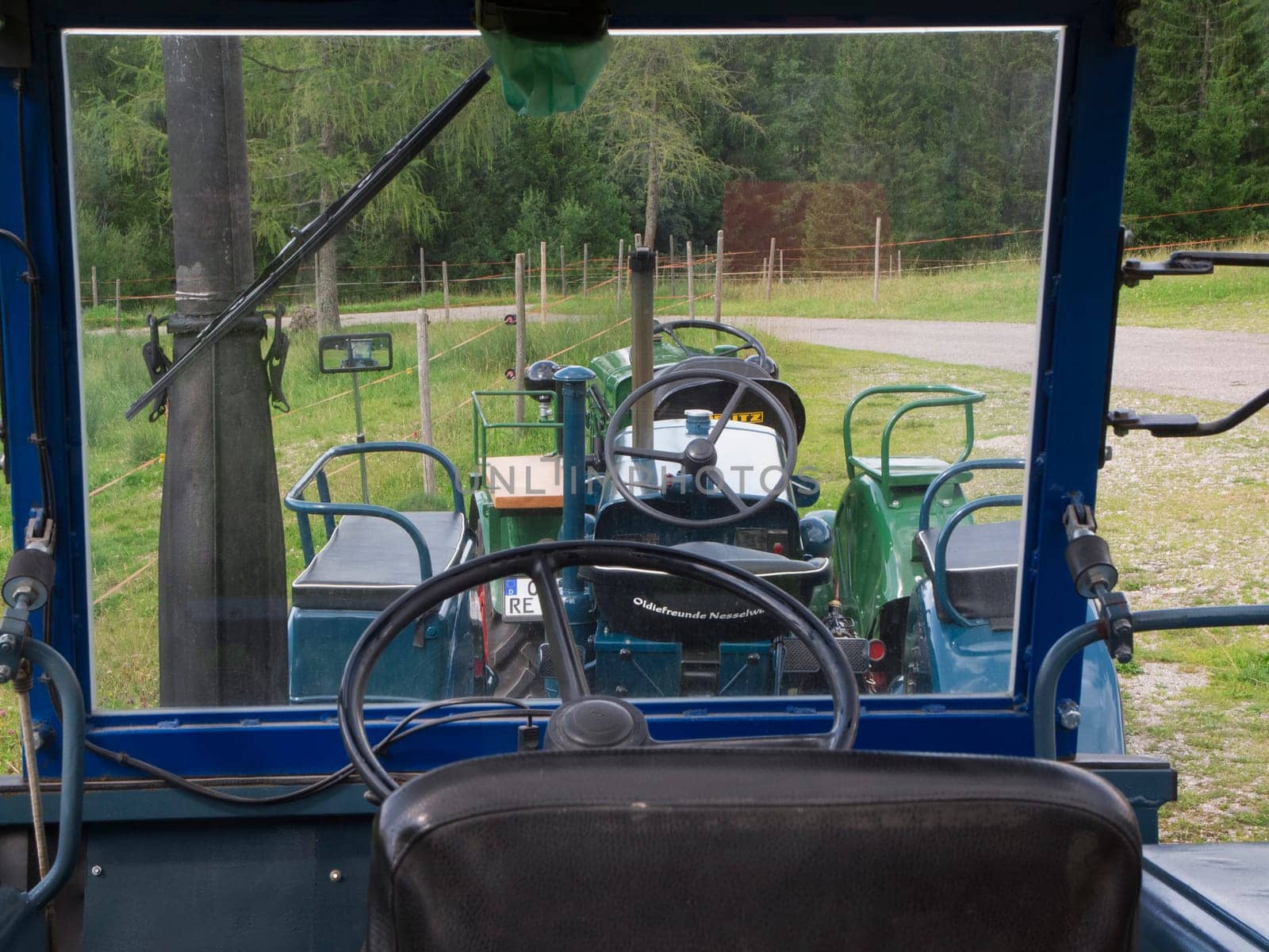 Nesselwang, Germany - July 23, 2020: Interior view with a view through the windshield of a green restored LANZ tractor aside from a veteran tractor.