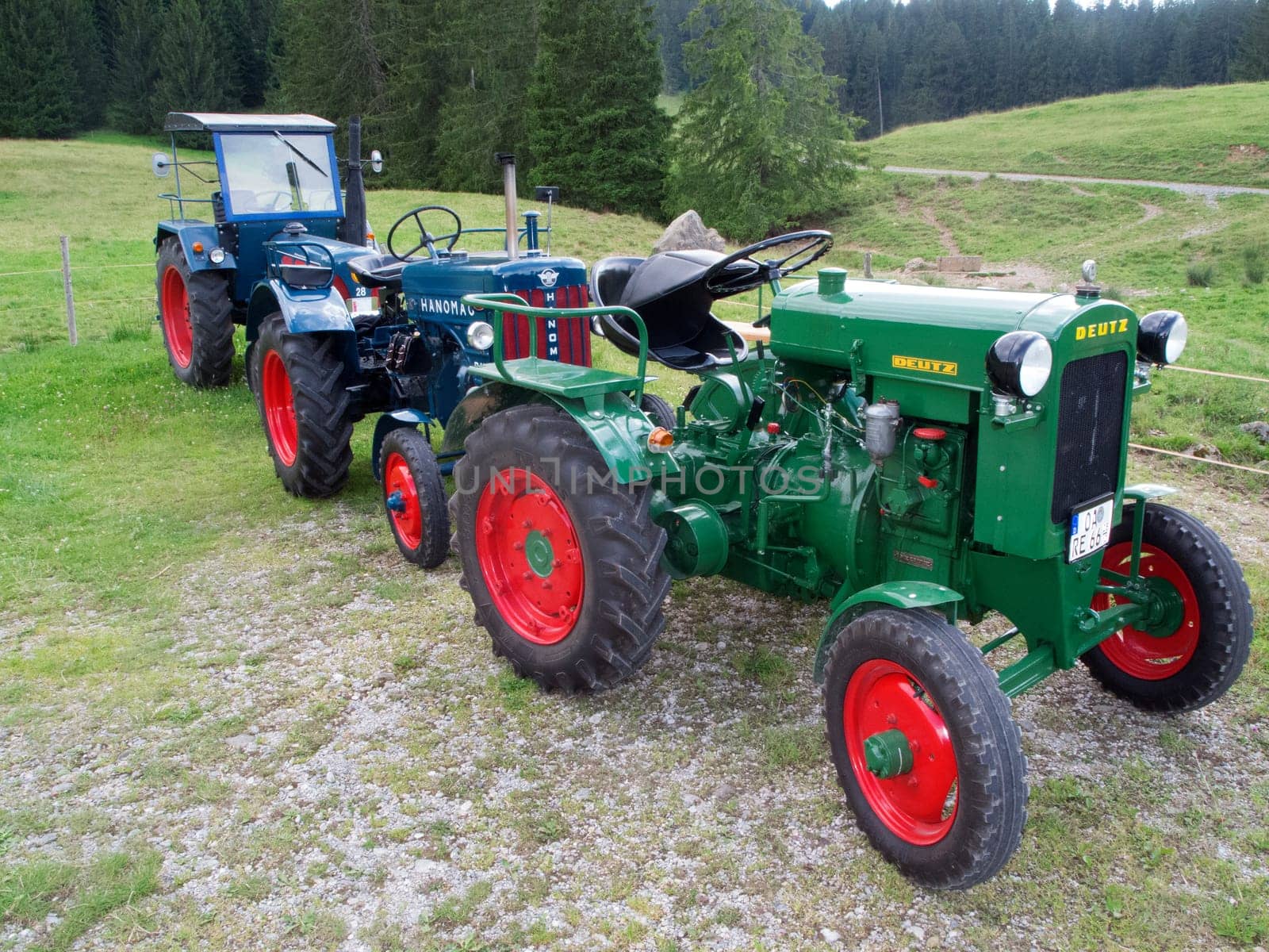 Haslach, Germany - July 23, 2020: Three old and restored tractors parked one behind the other on a hill near the Habacher Alpe and the Reichenbach holiday village in Bavaria.