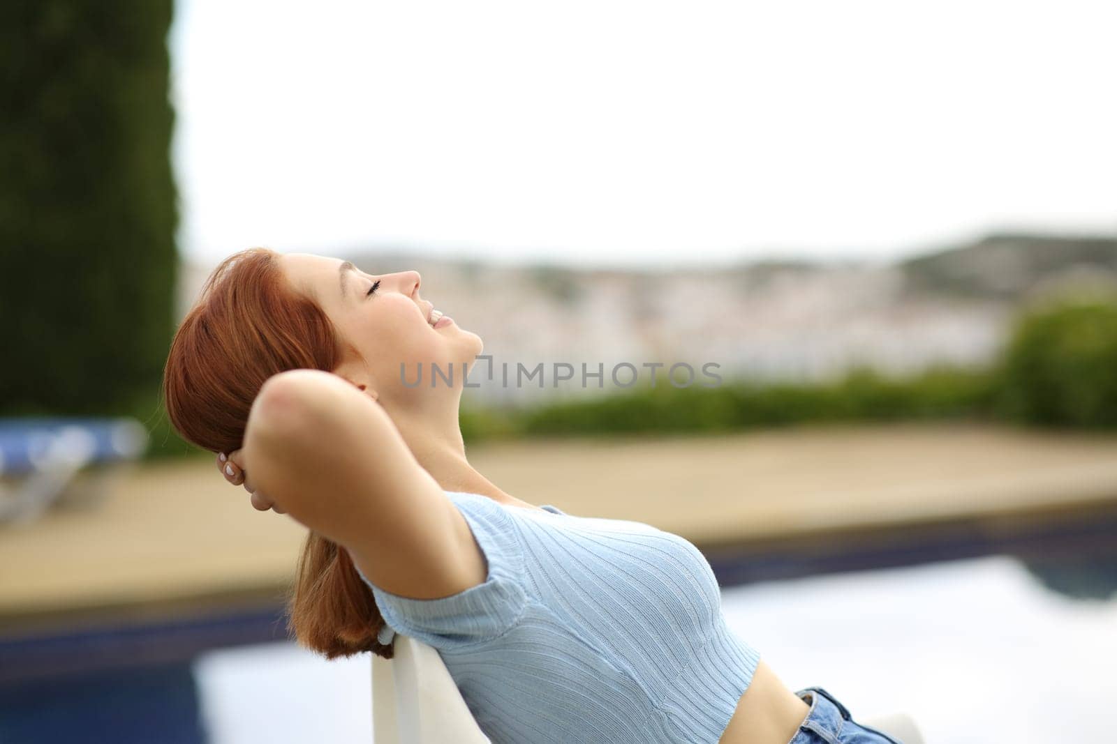 Happy woman resting sitting in a garden beside a pool