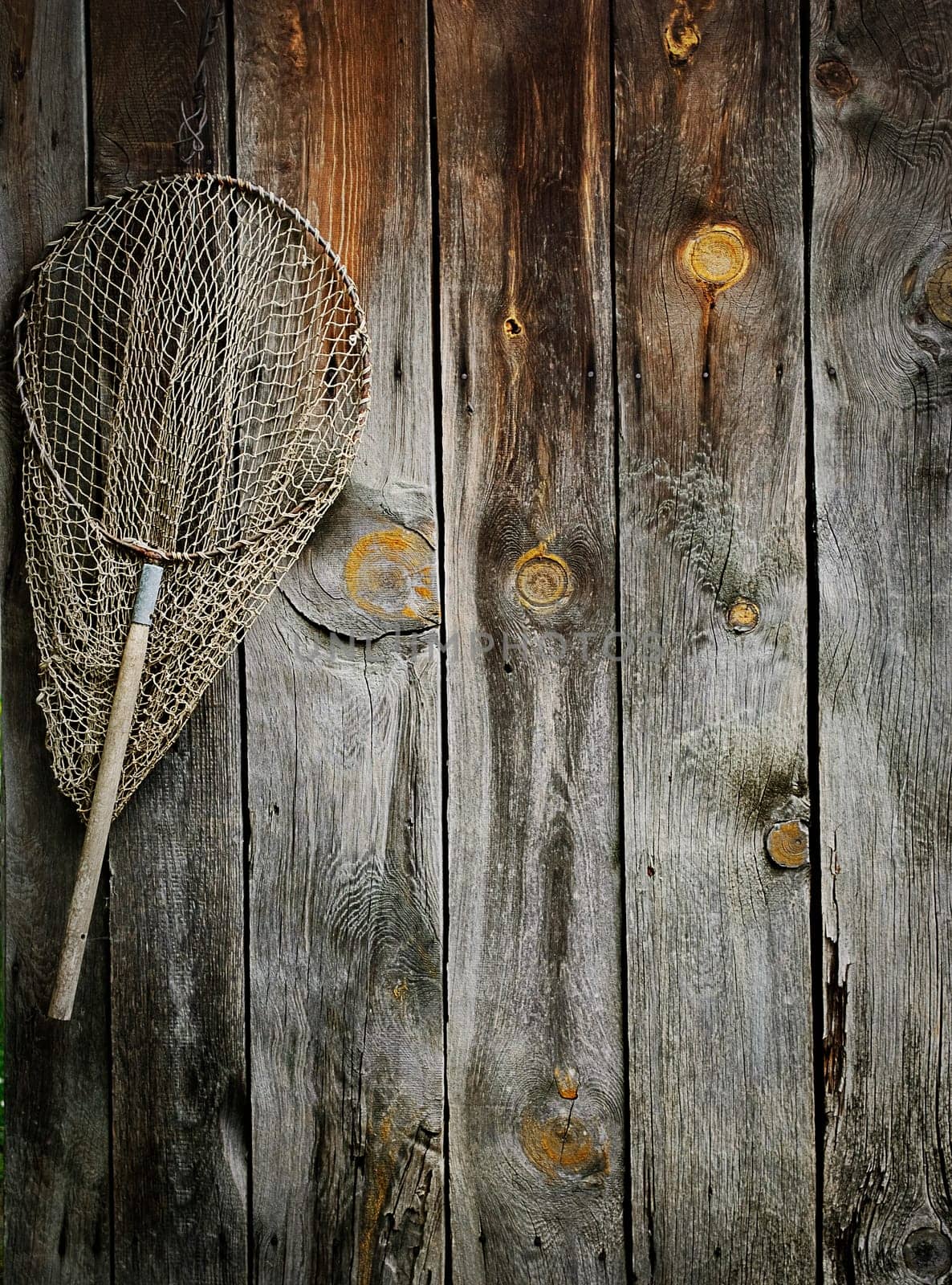 An old fishing net hanging on rustic wooden wall